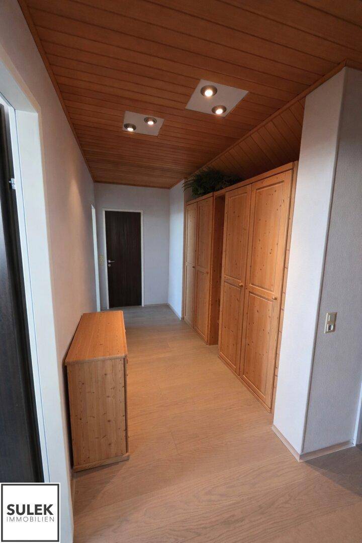 Flur mit Holzvertäfelung an der Decke, Laminatboden und praktischen Holzschränken.