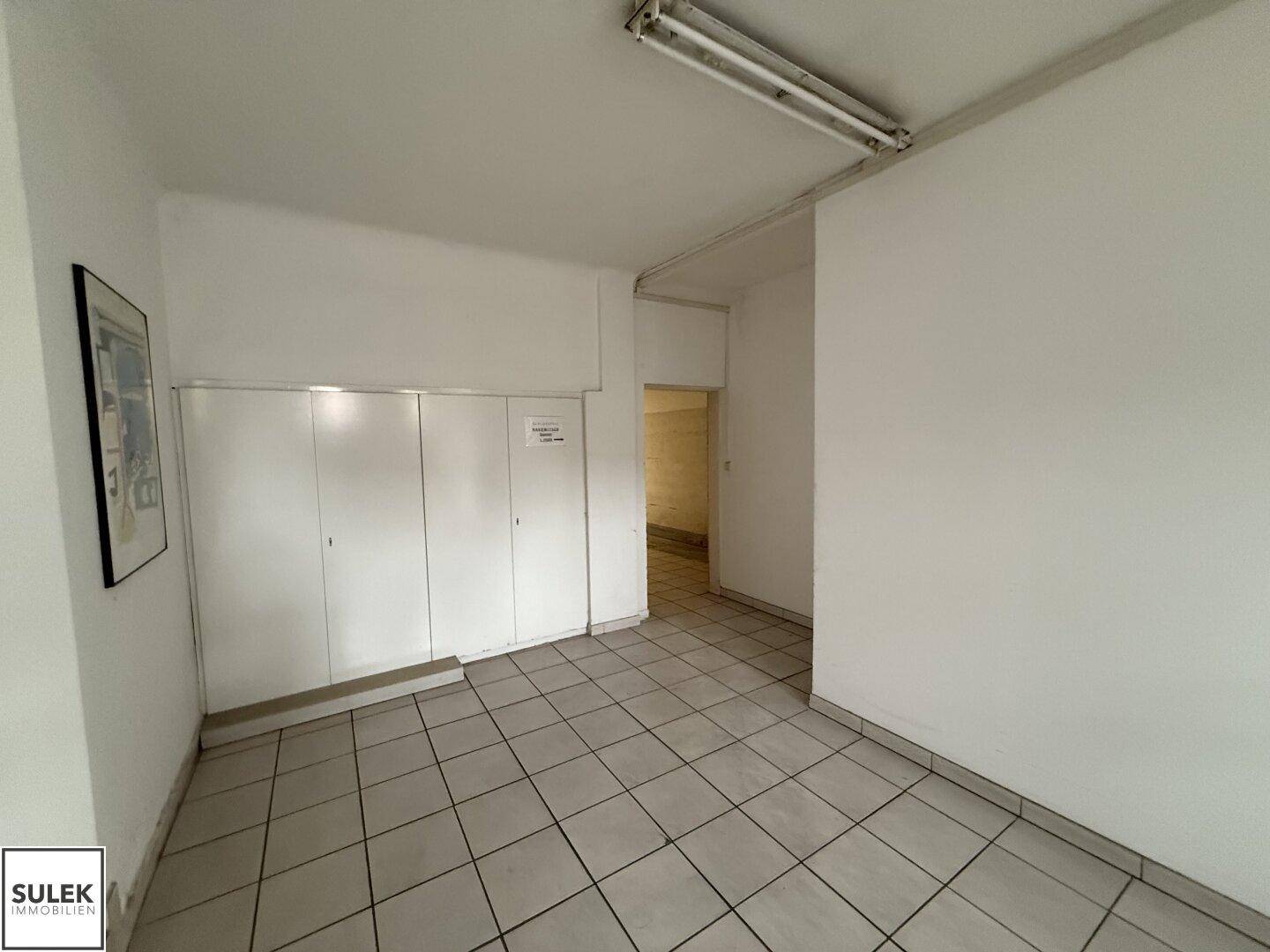 Flur mit Fliesenboden und weißen Schränken, der zu weiteren Räumen führt.
