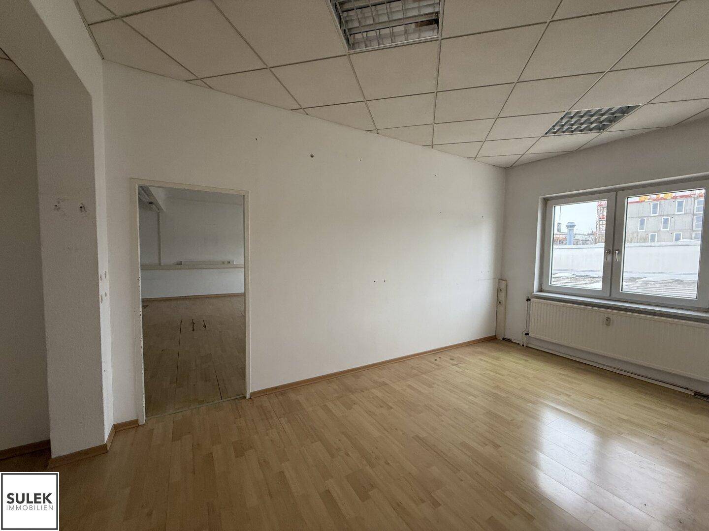 Leerer Büroraum mit abgehängter Decke und großen Fenstern, bietet vielseitige Nutzungsmöglichkeiten.