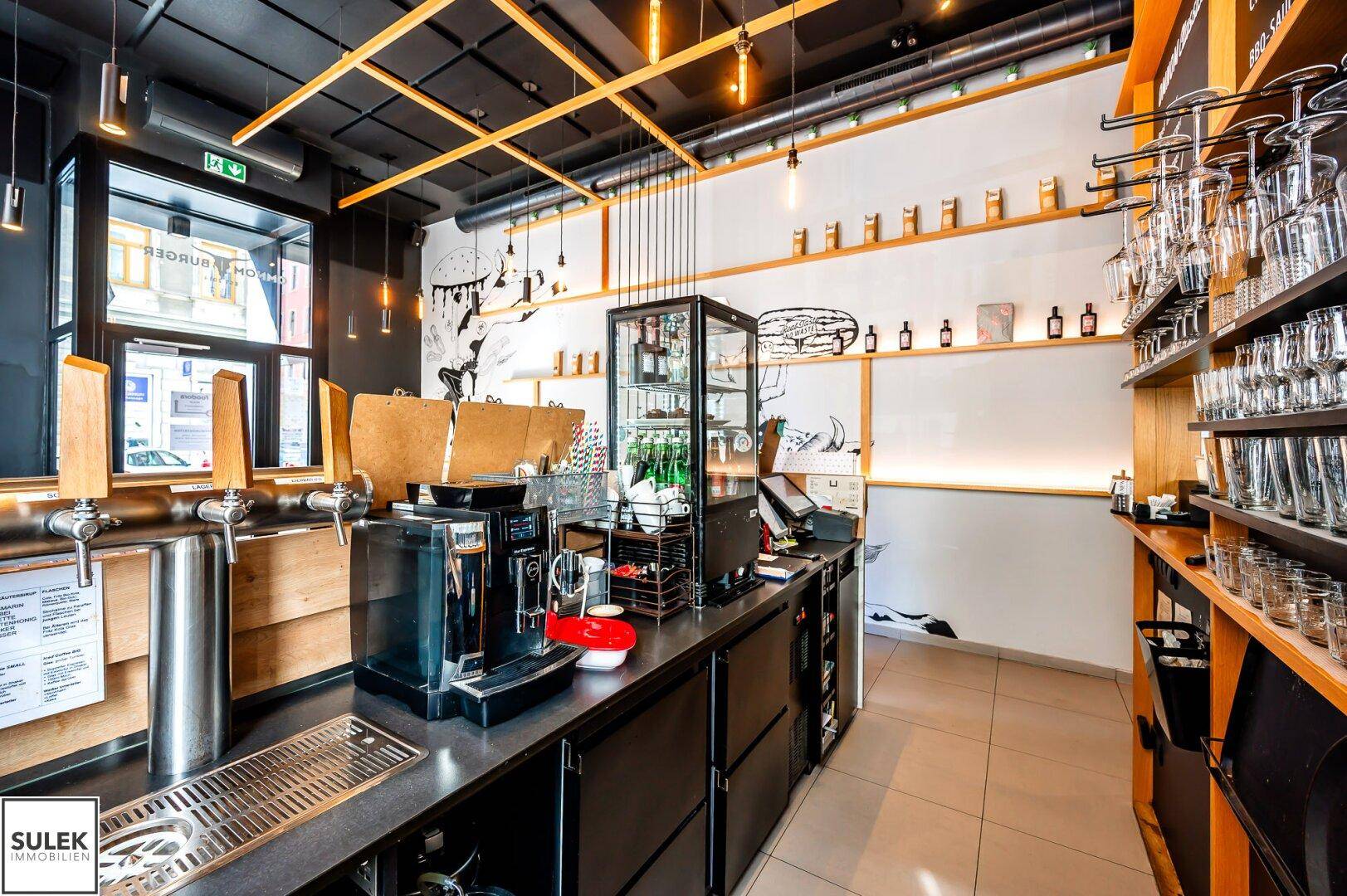 Detailansicht der Theke mit Zapfanlage, Kaffeemaschine und Gläserregalen, bereit für den Betrieb.