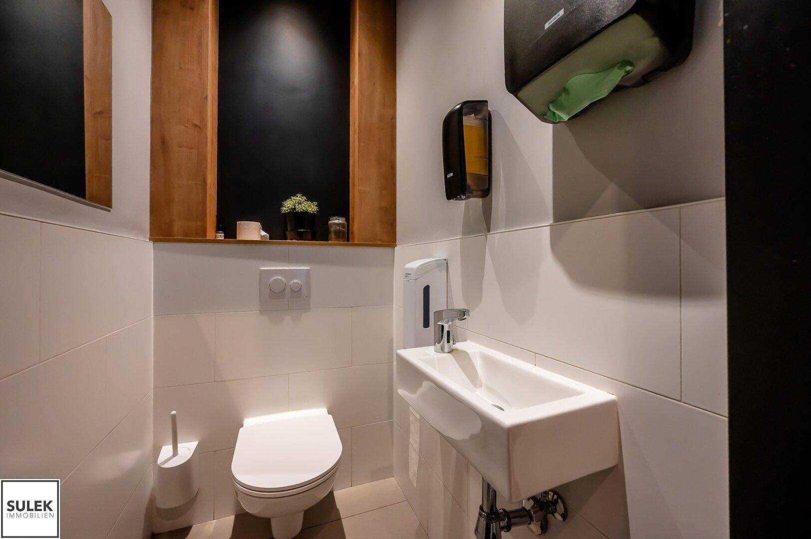 Sauberes und funktionales Gäste-WC mit modernem Waschbecken und weißen Wandfliesen.
