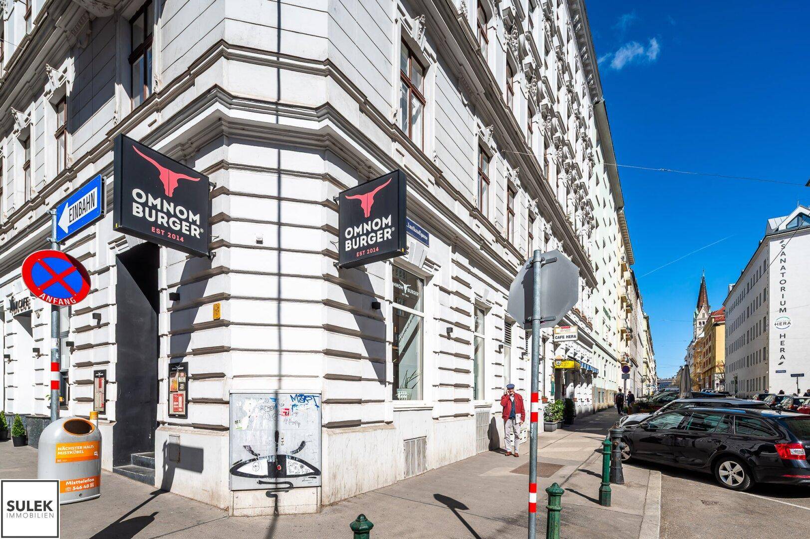 Straßenecke mit dem Eingang eines Restaurants in einem historischen Gebäude und umliegender Stadtansicht.