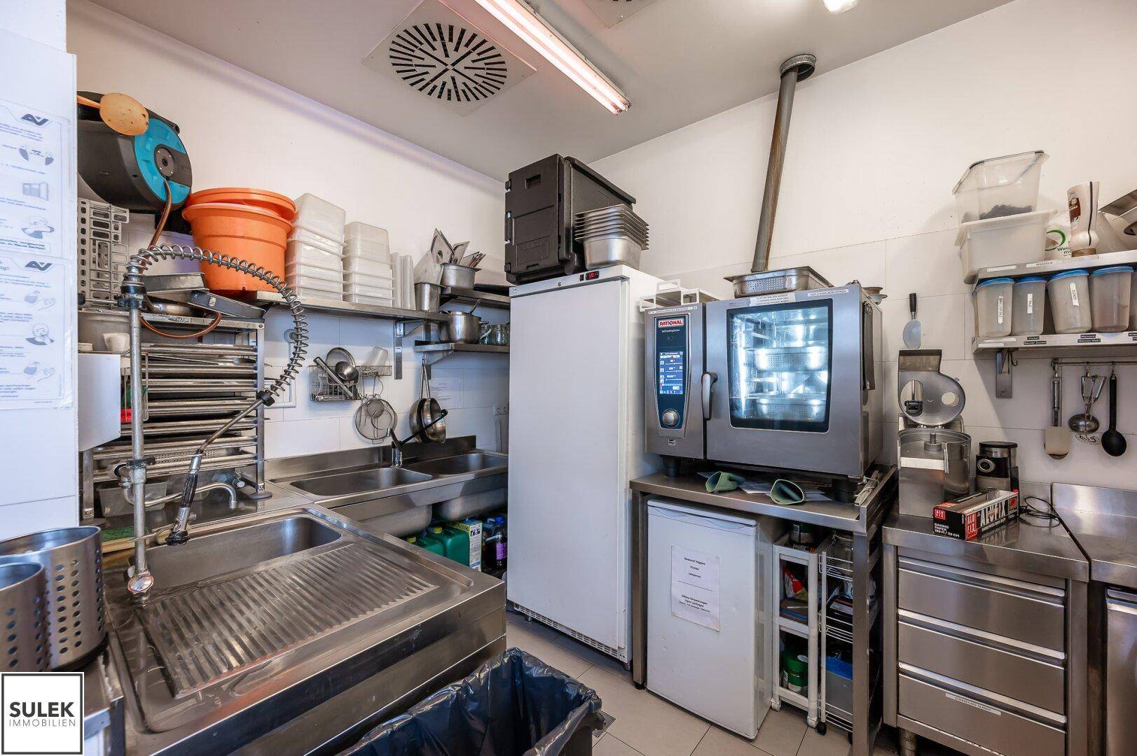 Professionelle Küche mit Edelstahlspülen, Konvektomat und Ablageflächen, optimiert für den Restaurantbetrieb.