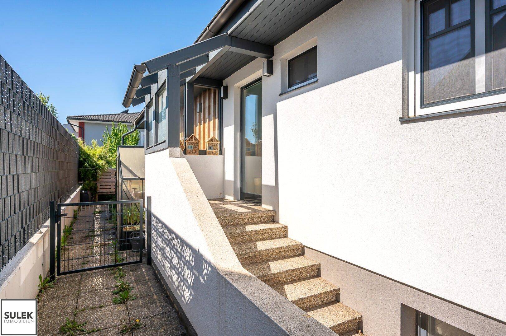 Eingangsbereich des Hauses mit Steintreppe und seitlichem Zugang zum Grundstück.