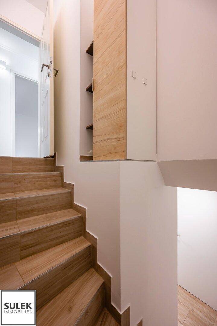 Holztreppe mit integrierten Regalen, die in die obere Etage führt und Stauraum bietet.