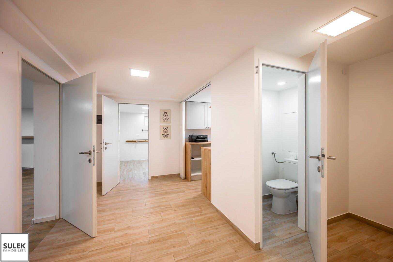 Heller Kellerbereich mit mehreren Türen und einem separaten WC, ausgestattet mit Fliesenboden.