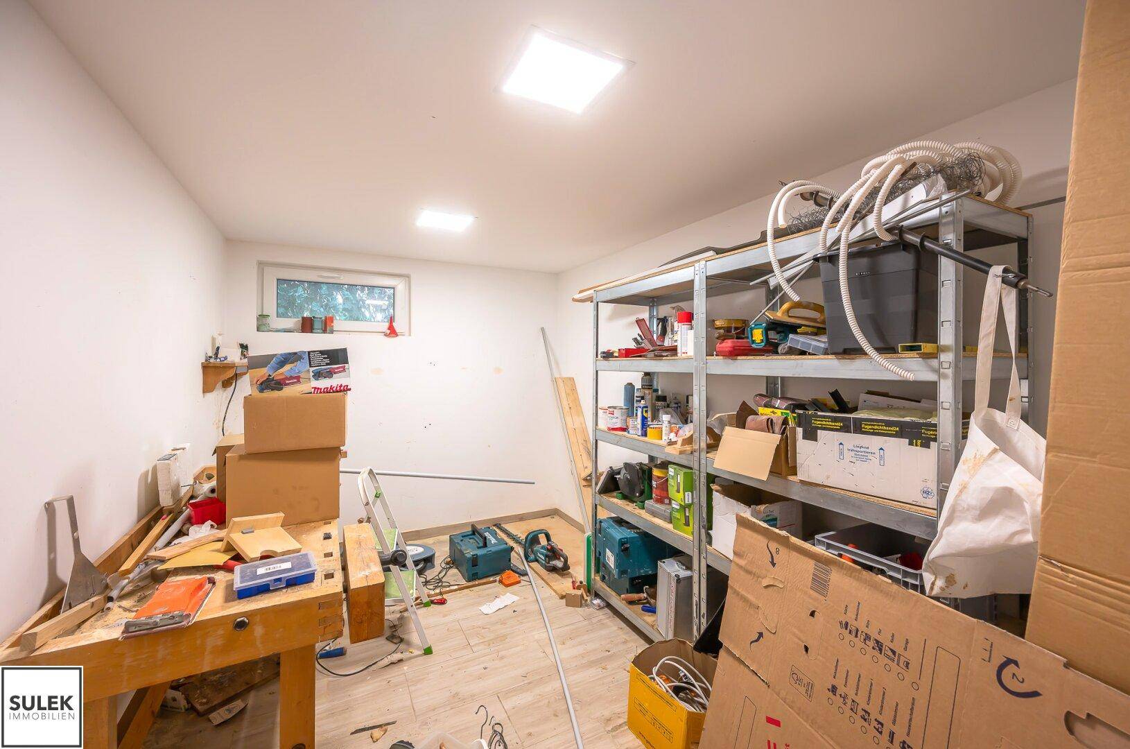 Heller Werkstattraum mit Werkbank, Regalen und viel Stauraum für Hobby und Arbeit.