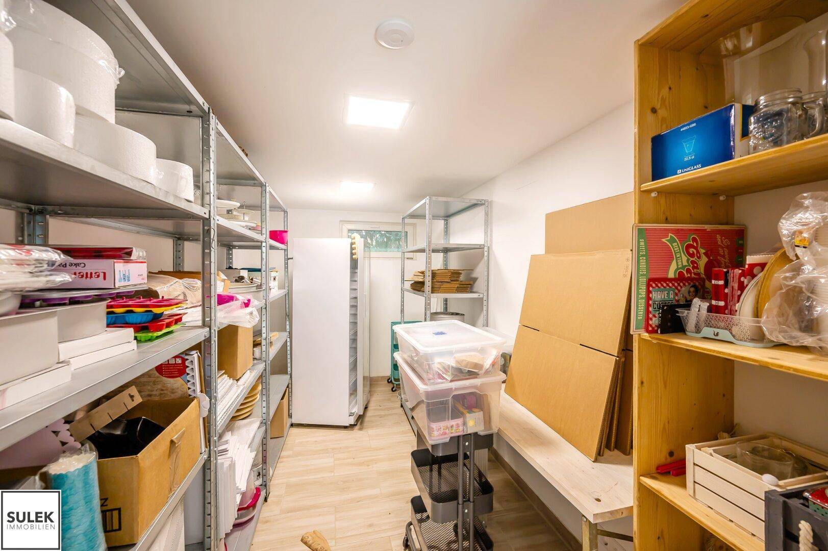Großer Abstellraum mit Metallregalen, Kühlschrank und zusätzlichem Stauraum.