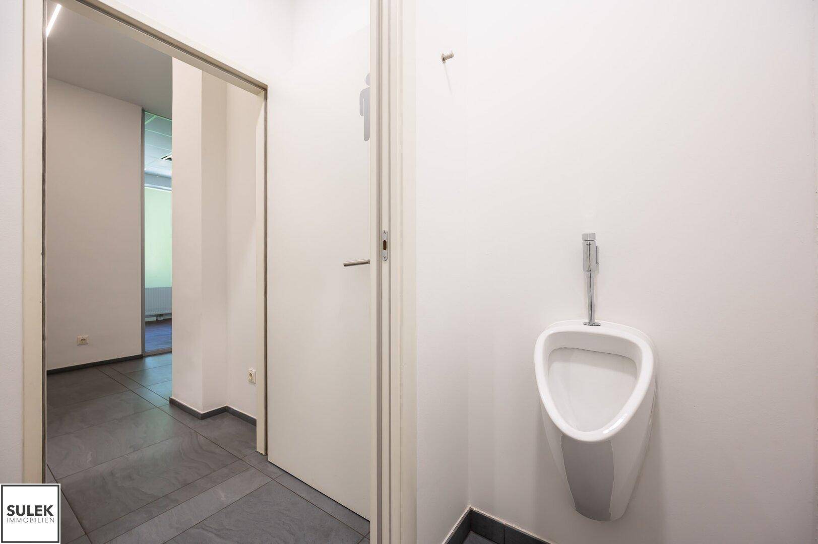 Moderner Toilettenraum mit Urinal und Waschbecken, in einem hellen und funktionalen Design gehalten.