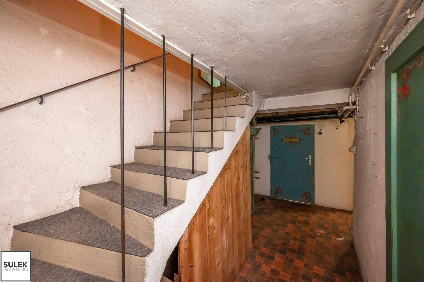Treppenhaus mit Zugang zu einem Kellerraum und rustikalen Elementen, das den Charme eines Altbaus widerspiegelt.
