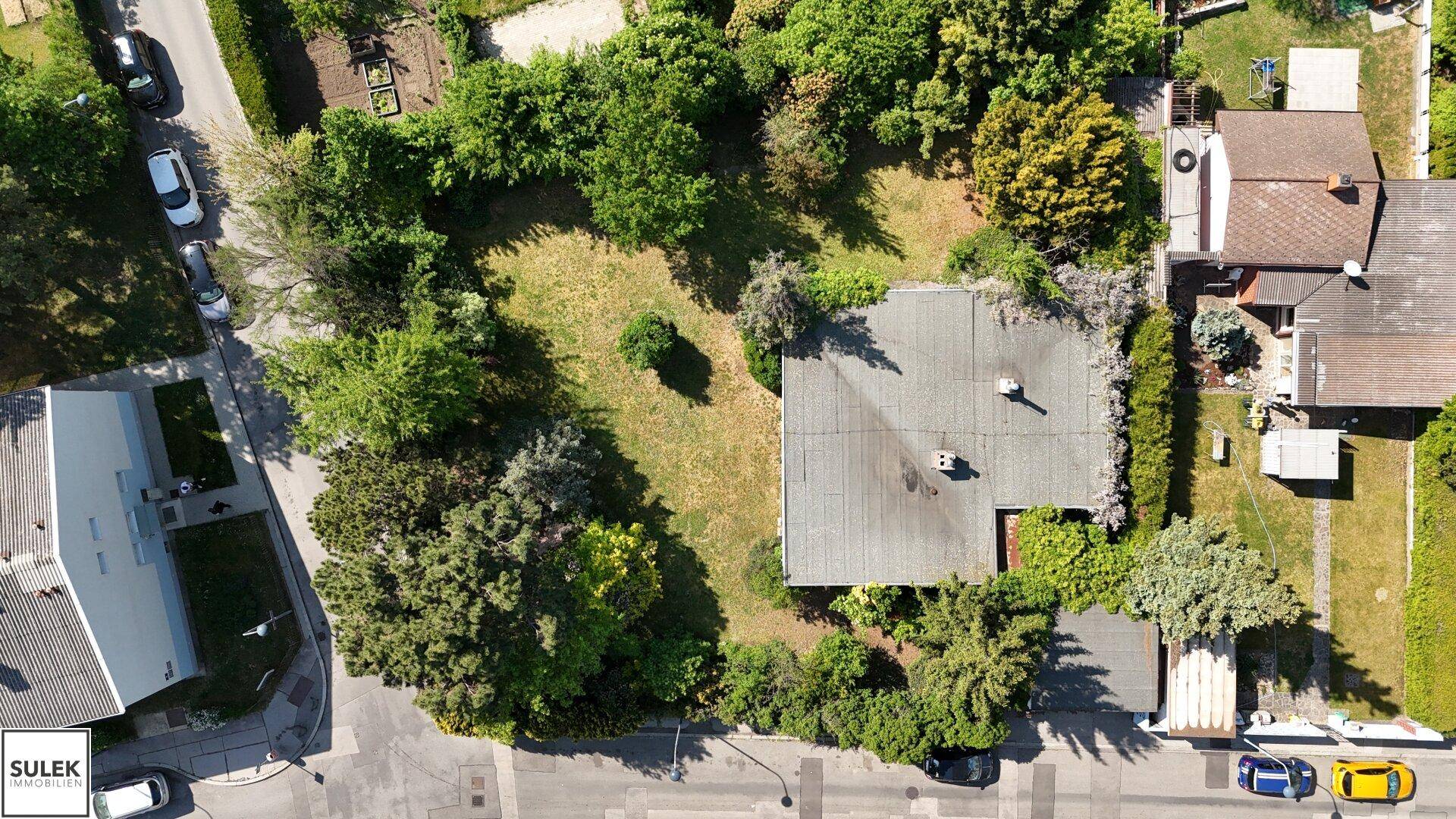 Luftaufnahme des Grundstücks mit einem Haus, großem Garten und umliegender Bebauung in einer grünen Umgebung.