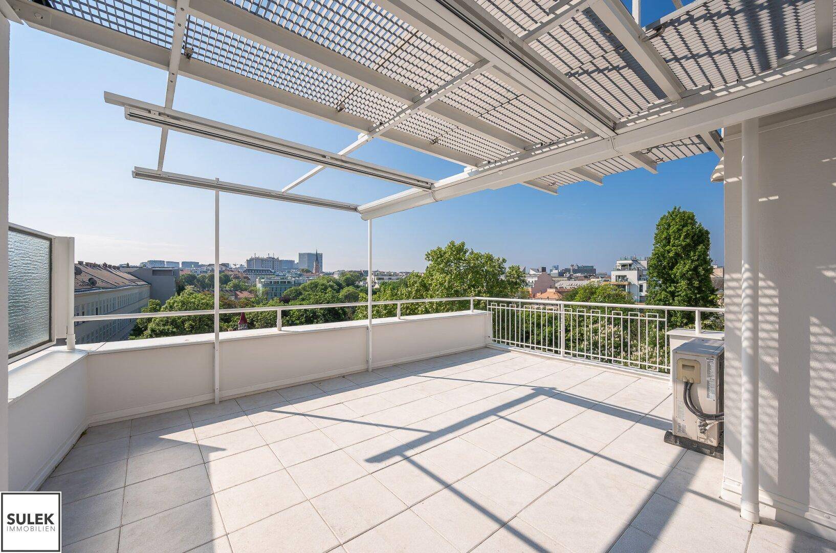 Große Dachterrasse mit Fliesenboden, Pergola und weitem Blick über die Stadt.