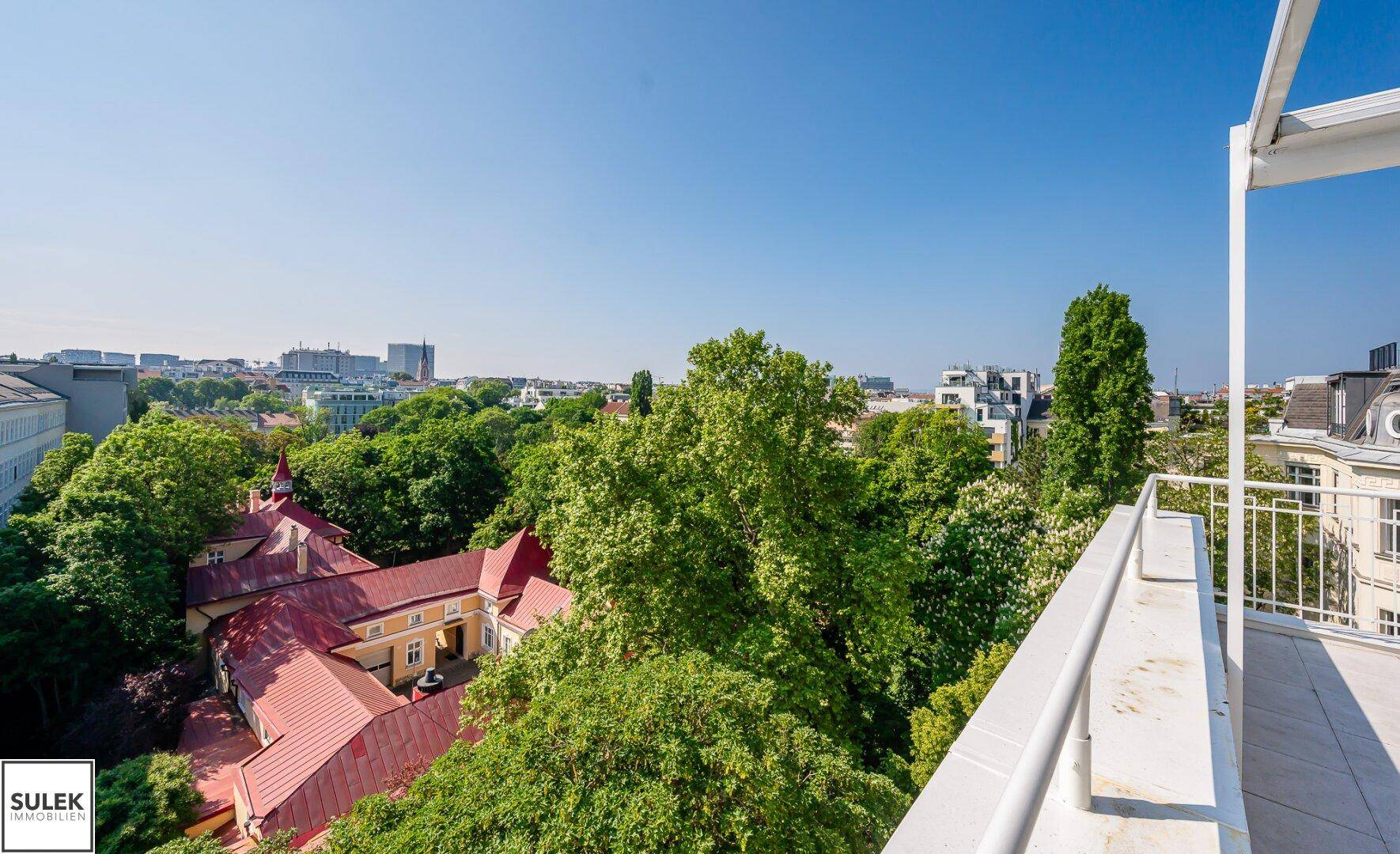 Panoramablick von der Dachterrasse auf grüne Bäume und die Stadtlandschaft.