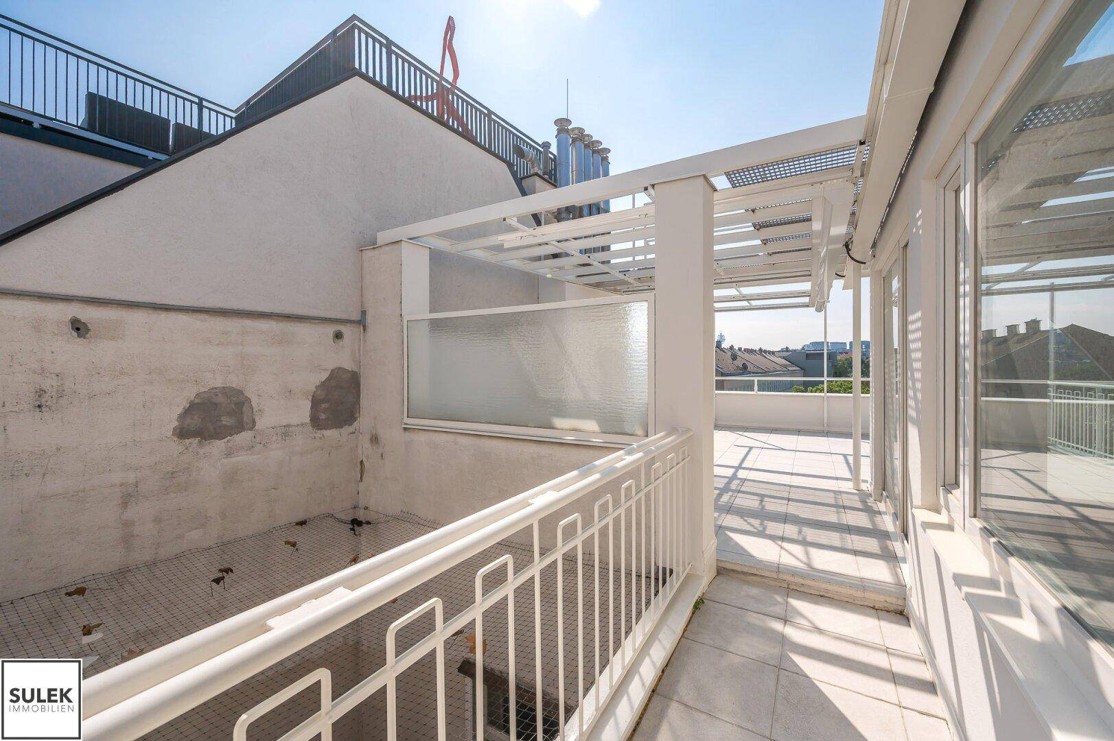 Teil der Dachterrasse mit Fliesenboden und Blick auf die umliegenden Gebäude.