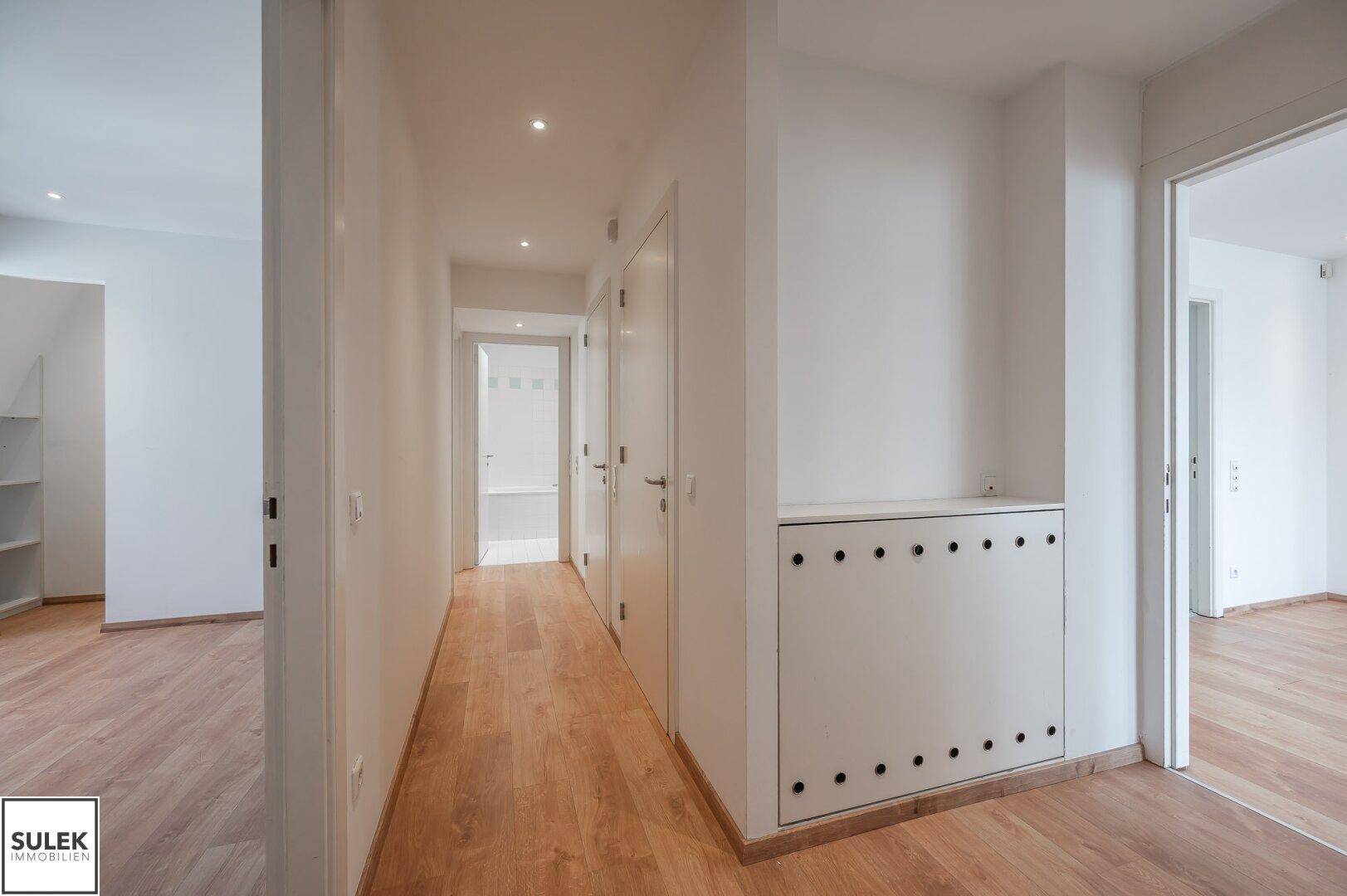 Heller Flur mit Holzparkettboden und Zugang zu verschiedenen Räumen der Wohnung.