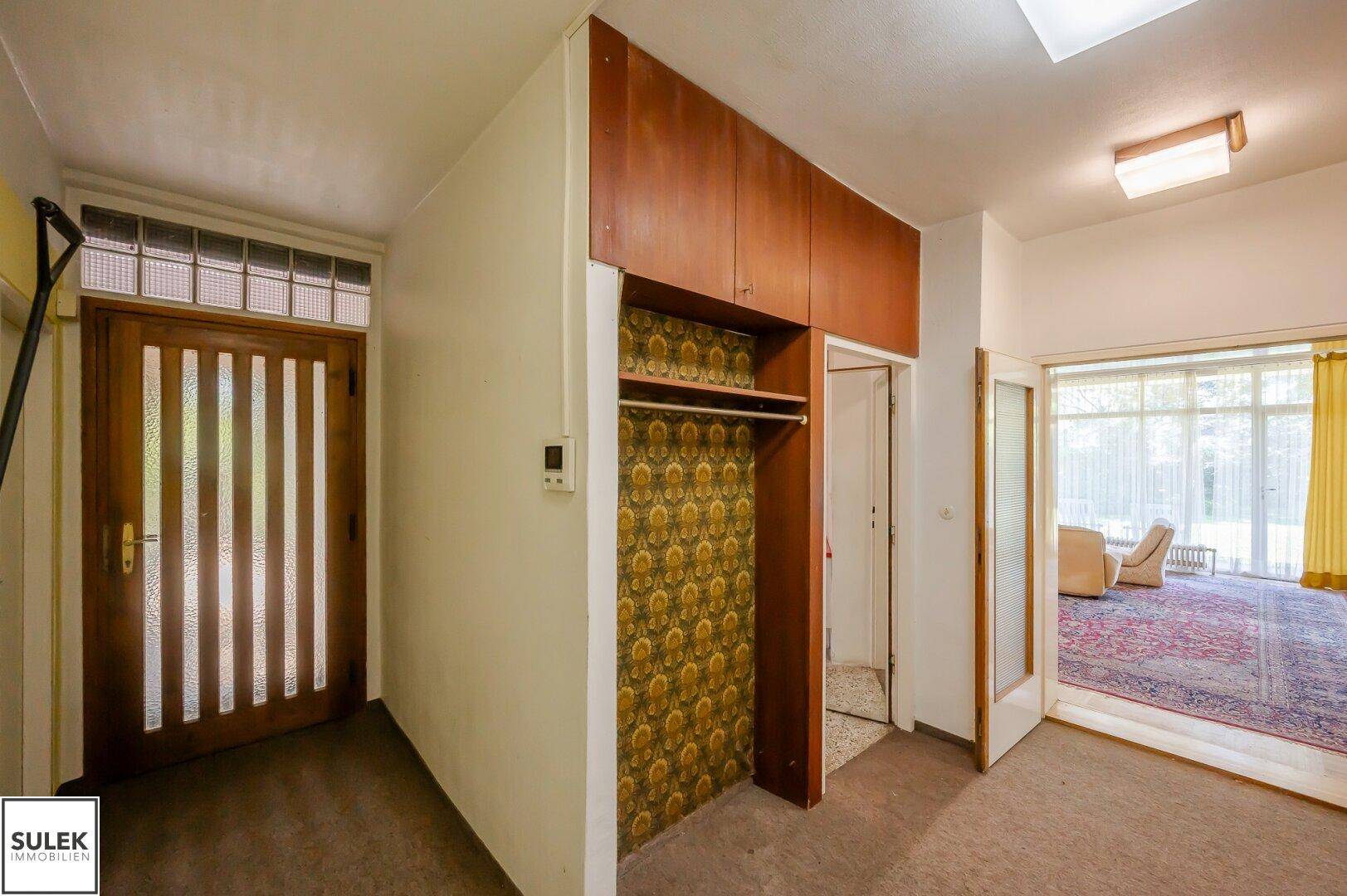 Flur mit Einbauschrank und Zugang zum Wohnbereich, mit Teppichboden.