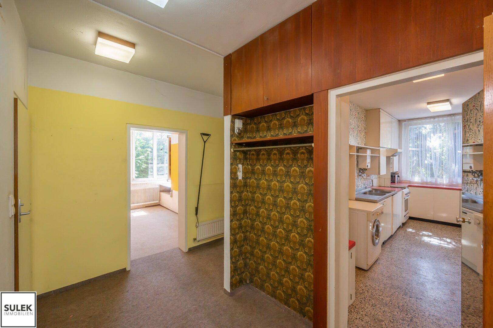 Flur mit Einbauschrank und Blick in die Küche, mit gelben Wänden.