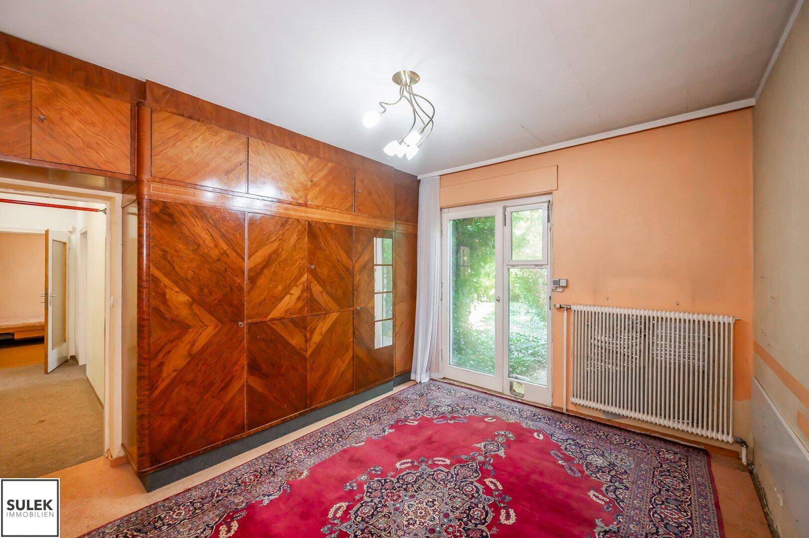 Schlafzimmer mit Einbauschrank aus Holz und Zugang zum Garten.
