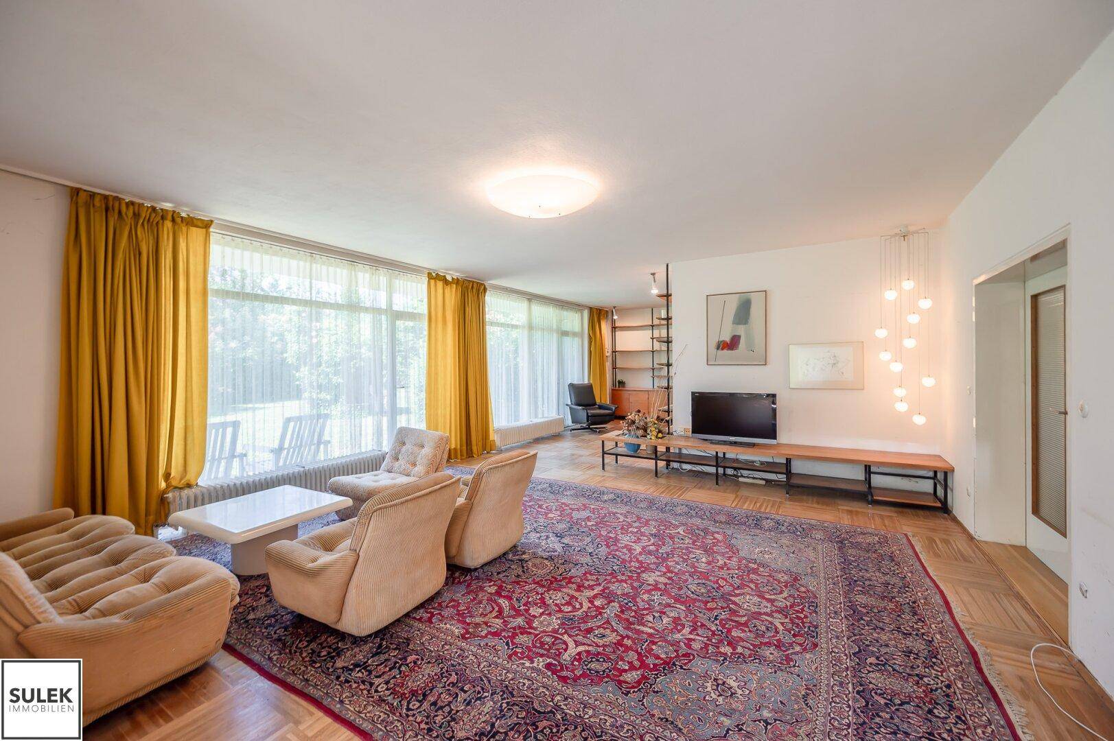 Helles Wohnzimmer mit Parkettboden, großen Fenstern und moderner Dekoration.
