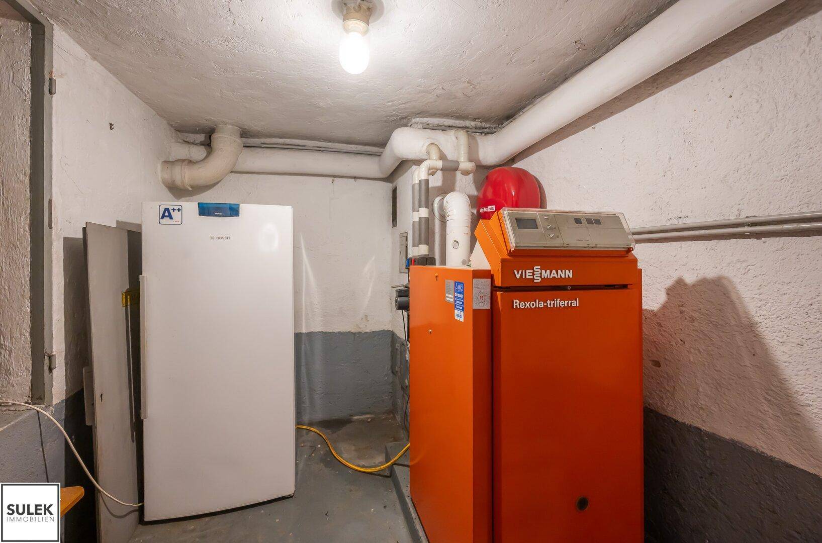 Ein Heizungsraum im Keller mit einem modernen Viessmann Heizsystem und einem zusätzlichen Kühlschrank.