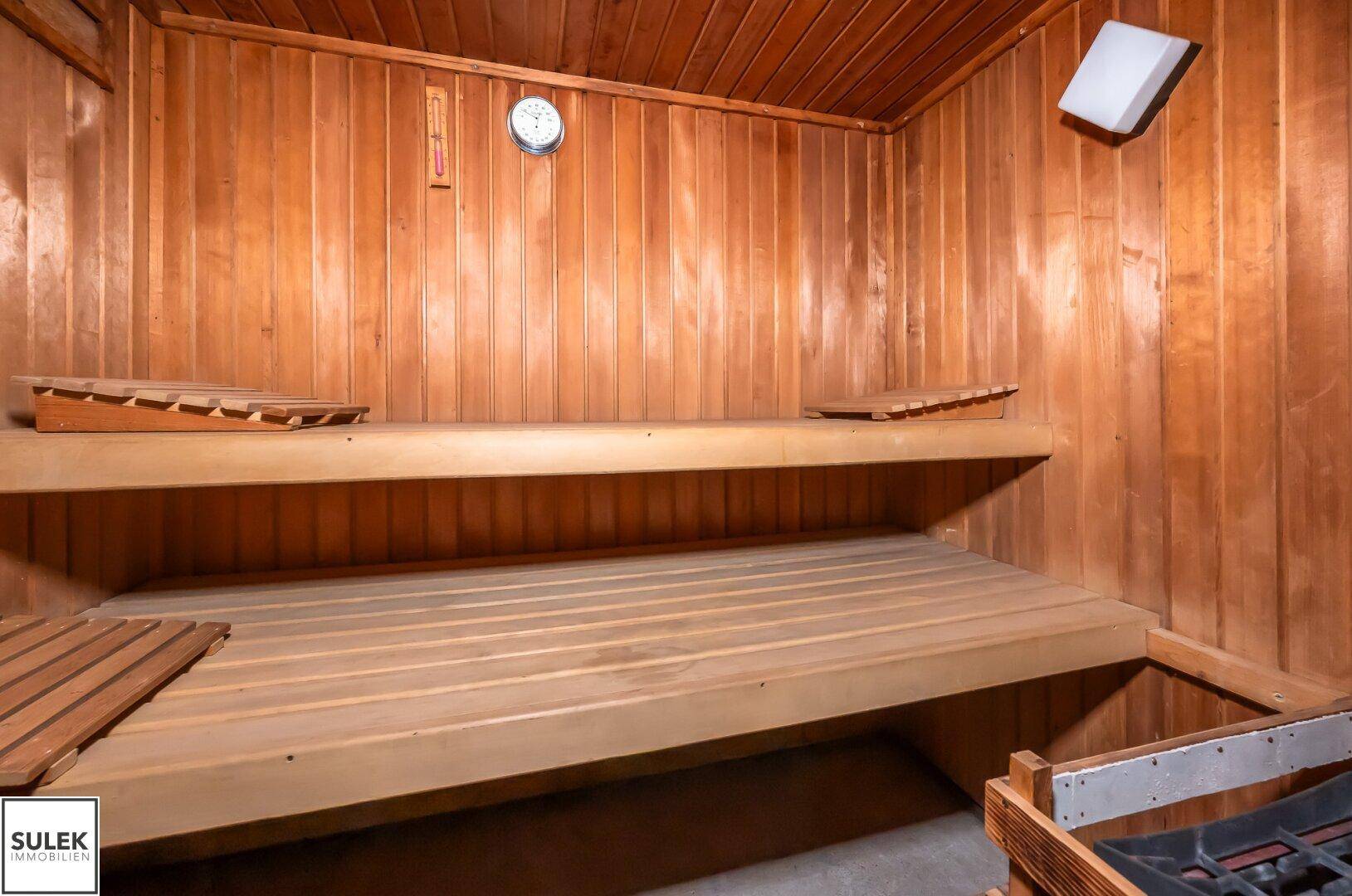 Eine traditionelle Holzsauna mit mehreren Bänken und einem Saunaofen für entspannende Momente.