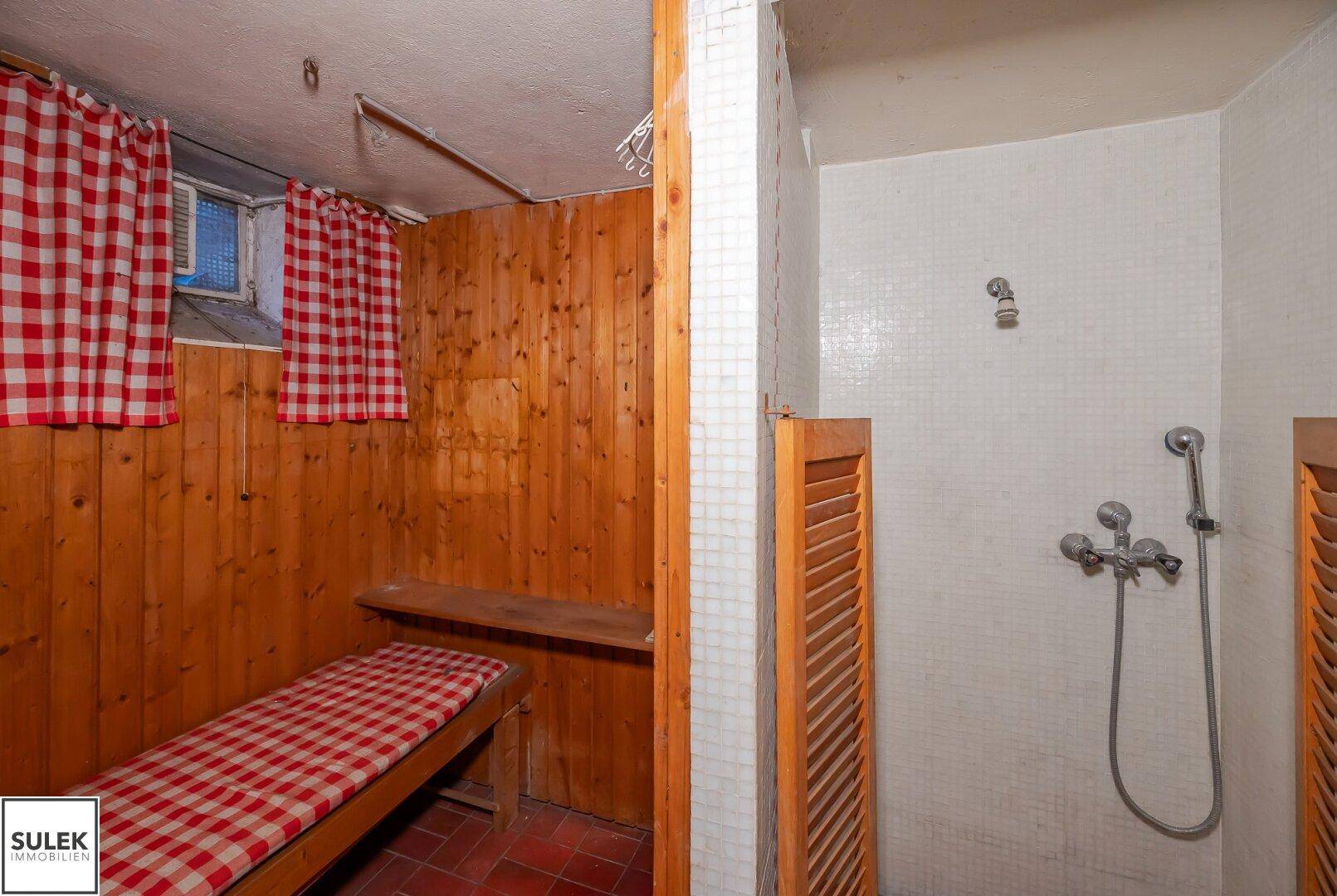 Ein Saunabereich mit Holzverkleidung und einer angrenzenden Duschkabine mit karierten Vorhängen.