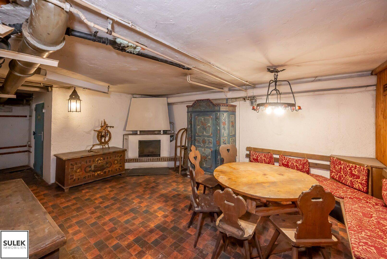 Ein rustikaler Kellerraum mit Kamin, Holztisch und Sitzbänken, ideal für gesellige Runden.