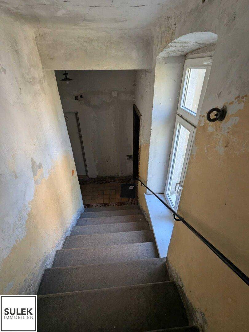 Treppenhaus mit abgenutzten Stufen und einem Fenster, das Licht hereinlässt.