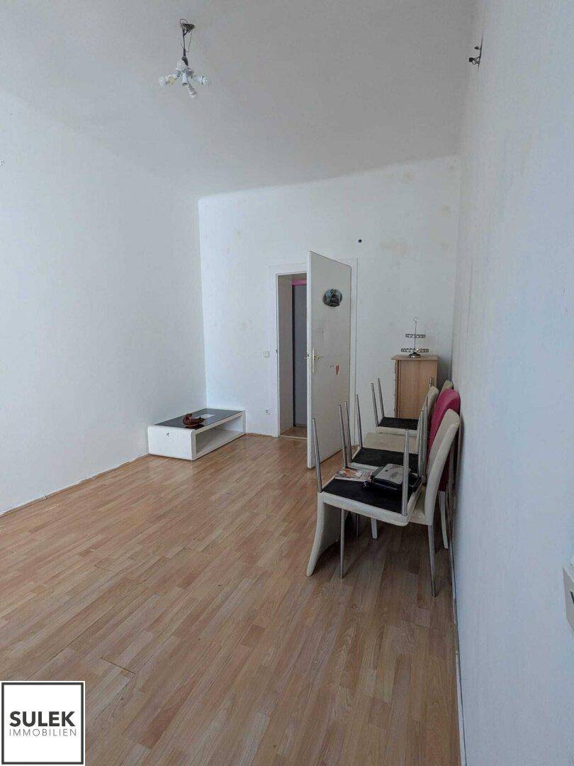 Heller Raum mit Holzfußboden, weißen Wänden und einfachen Möbeln.