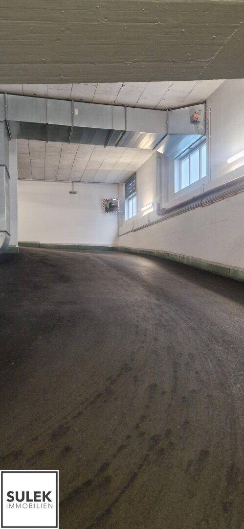 Zufahrtsrampe zur Tiefgarage mit natürlichem Lichteinfall durch Fenster.