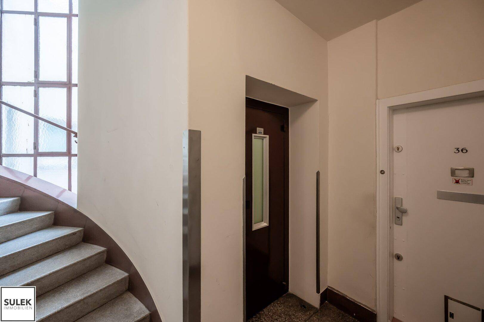 Treppenhaus und Aufzug in einem Mehrfamilienhaus, mit klassischer Architektur.