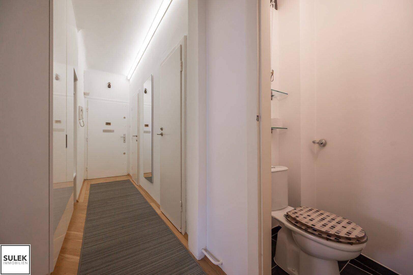 Separates WC im Flurbereich mit Toilette und Spiegel, funktional gestaltet.