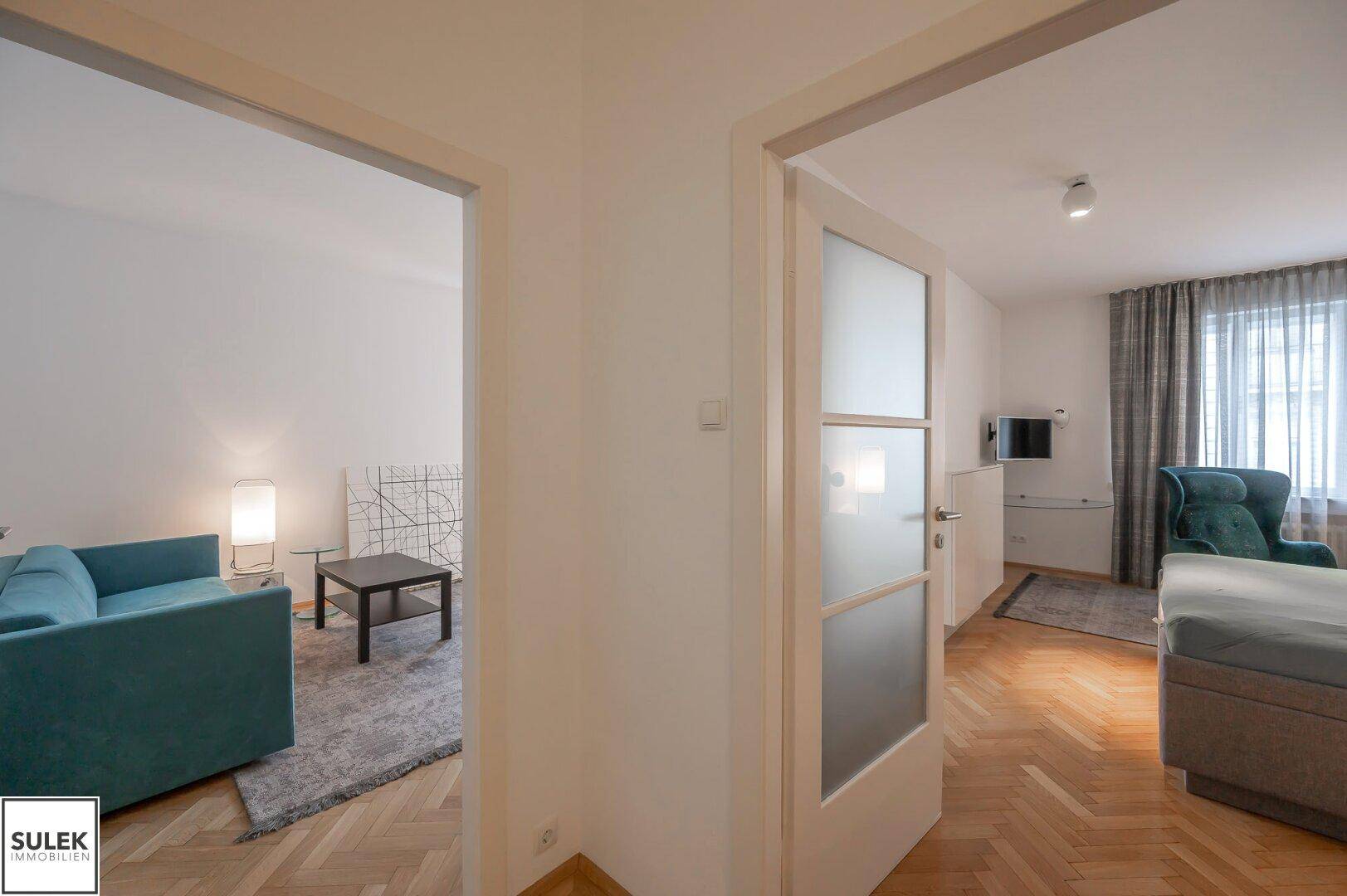 Flur mit Durchgang zu Wohnzimmer und Schlafzimmer, mit heller Tür.