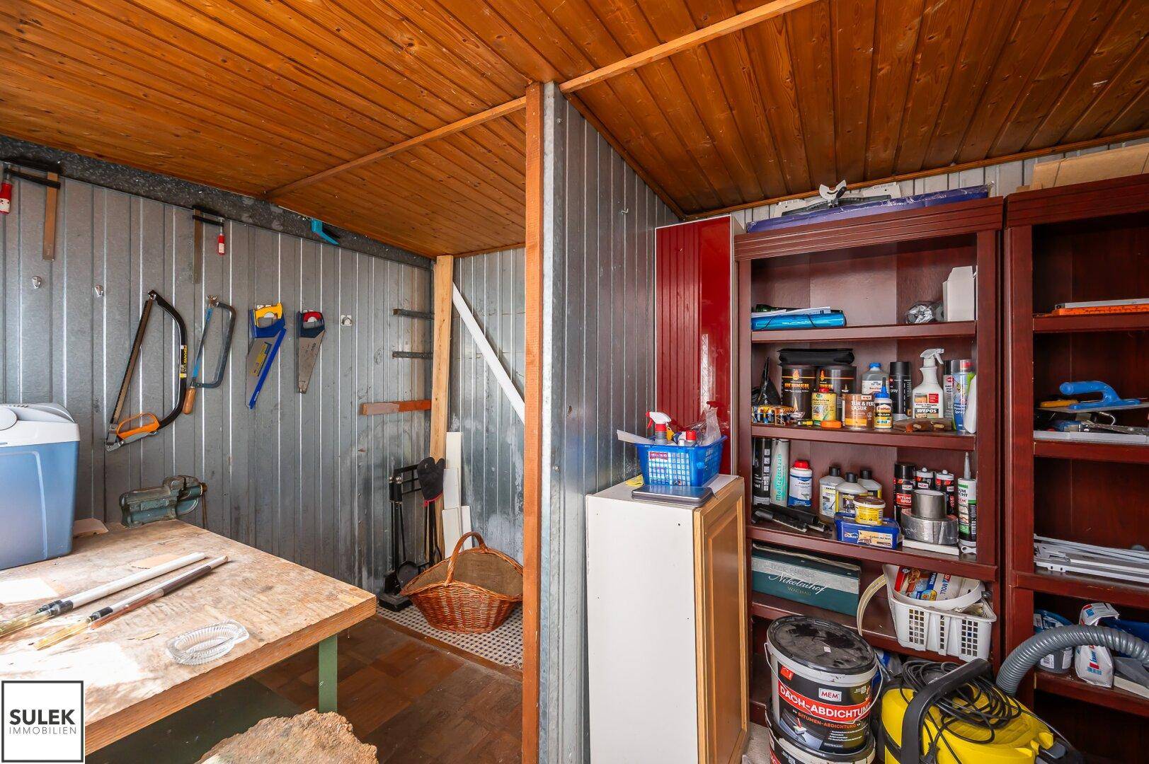 Innenansicht eines praktischen Abstellraums mit Holzdecke und Regalen für Werkzeuge.