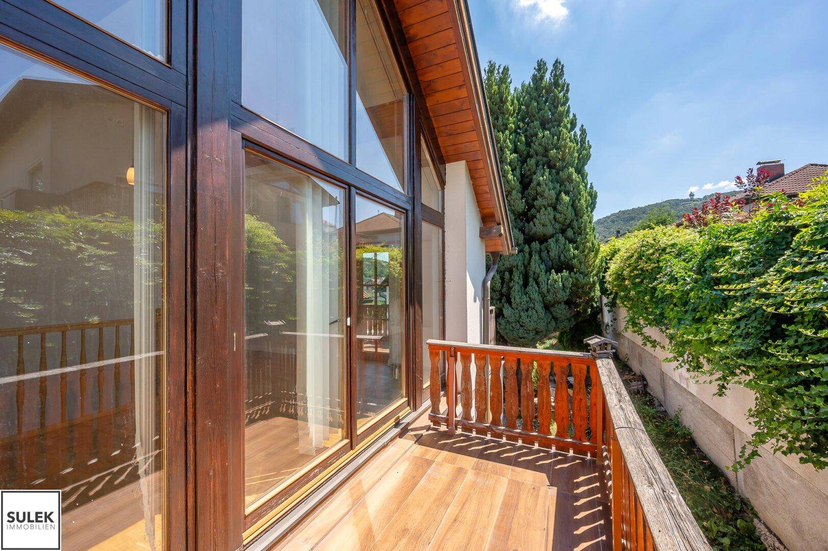Schmaler Holzbalkon mit traditionellem Geländer und Blick auf die umliegende Natur.