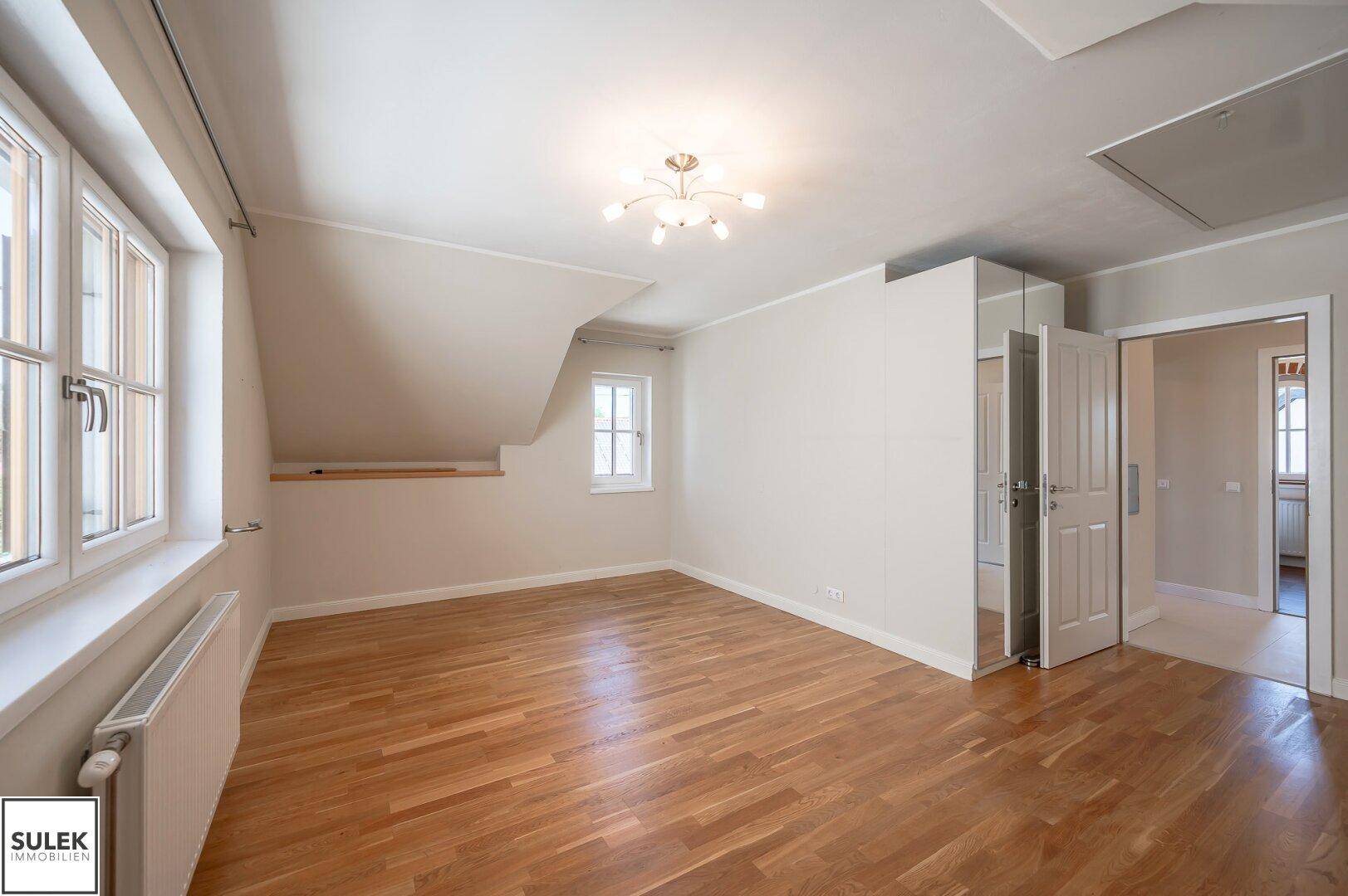 Geräumiges Schlafzimmer mit Holzboden, Dachschrägen und Einbauschränken.
