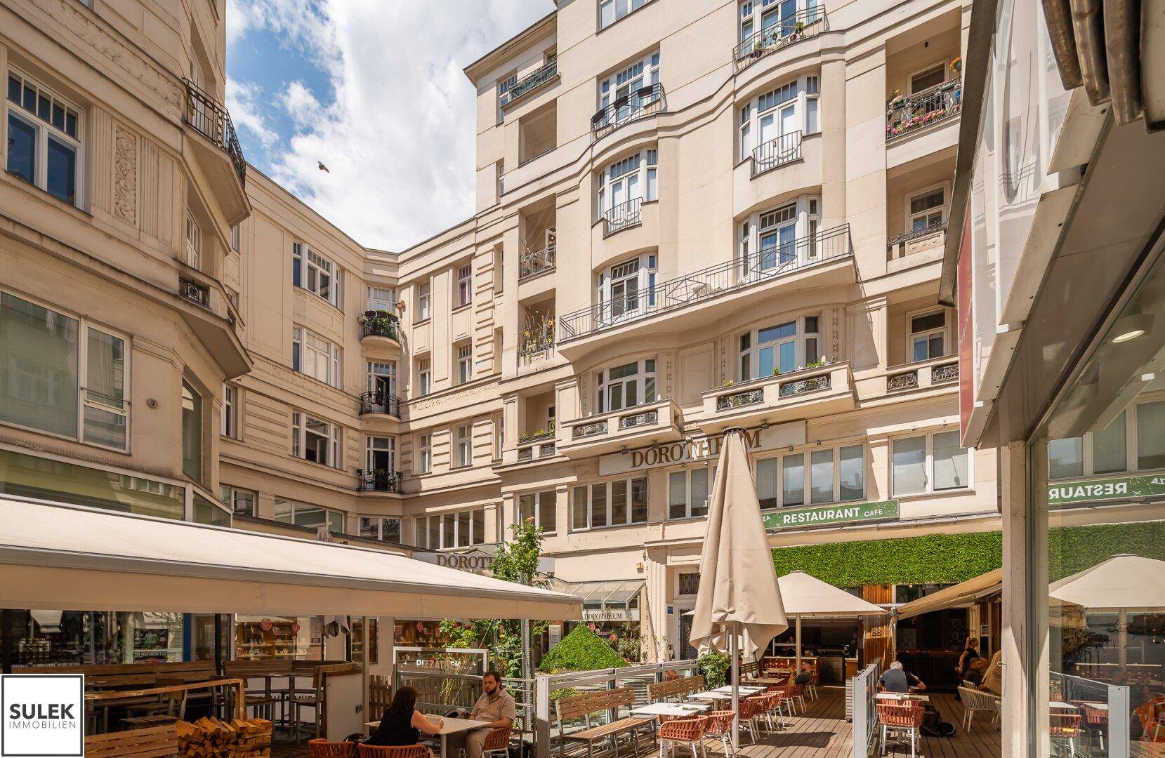 Ansicht einer charmanten Gasse mit Restaurants und Geschäften, umgeben von historischen Gebäuden.
