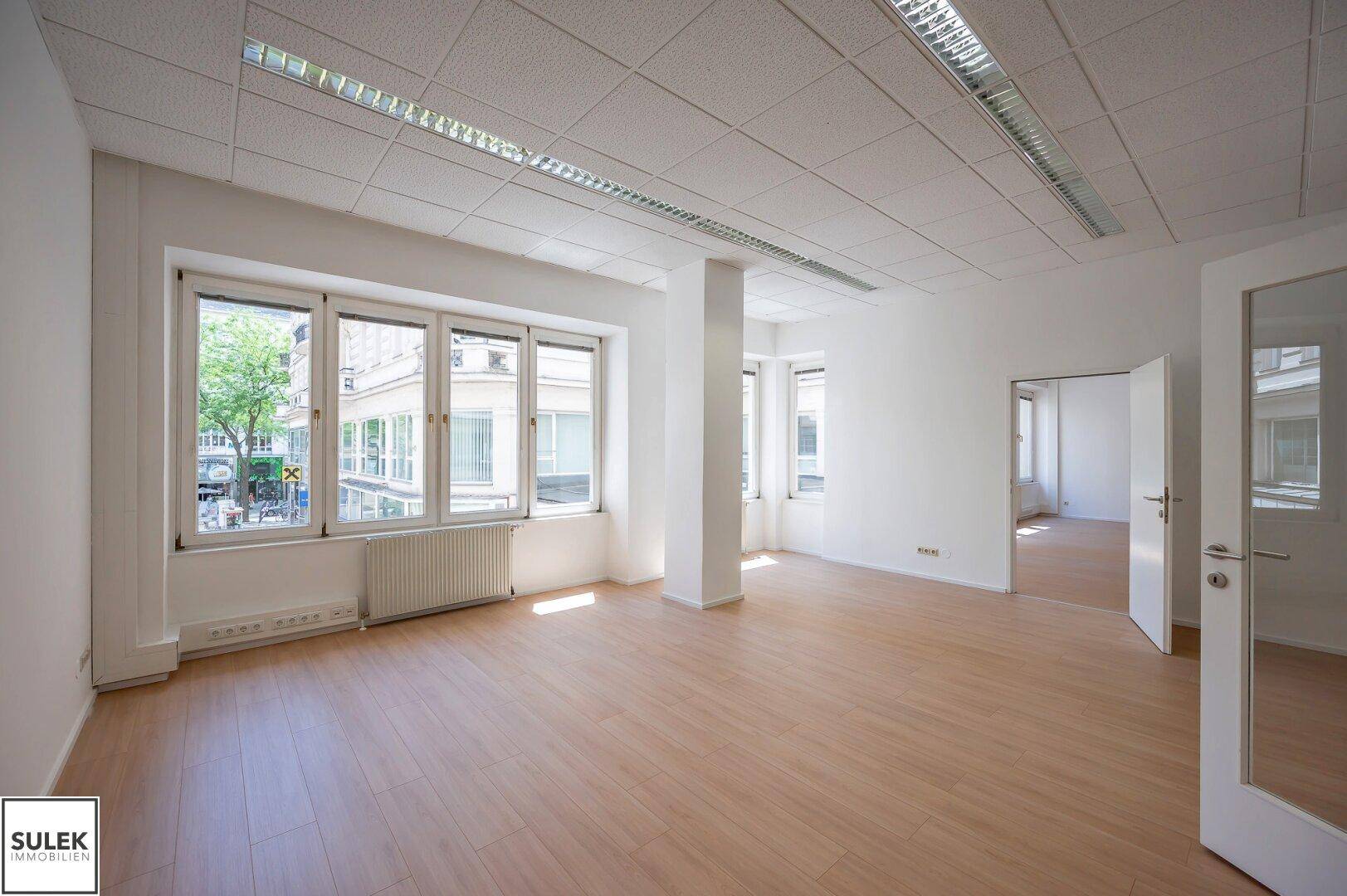 Großes, helles Büro mit vielen Fenstern, die viel Tageslicht hereinlassen, und einem Säulenakzent.