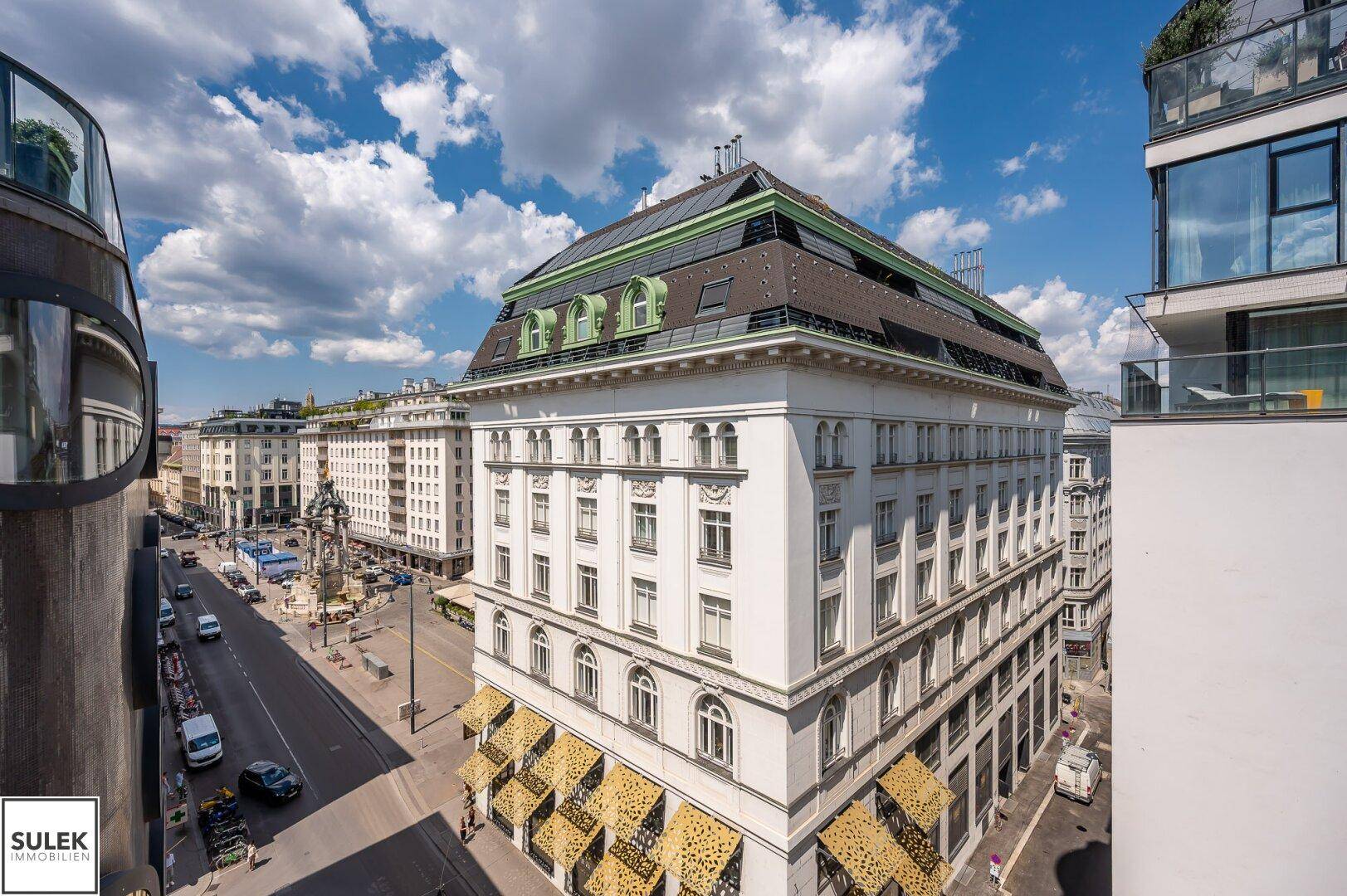 Luftaufnahme einer belebten Stadtstraße mit historischen Gebäuden und modernen Dächern.