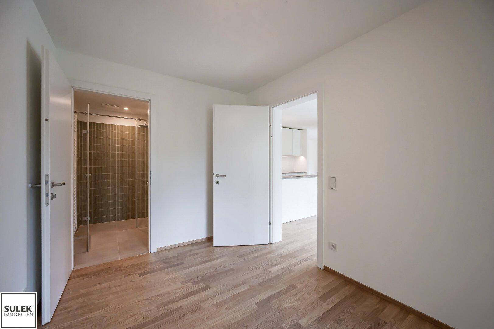 Flur mit Holzboden und Zugang zu verschiedenen Räumen, inklusive Badezimmer.