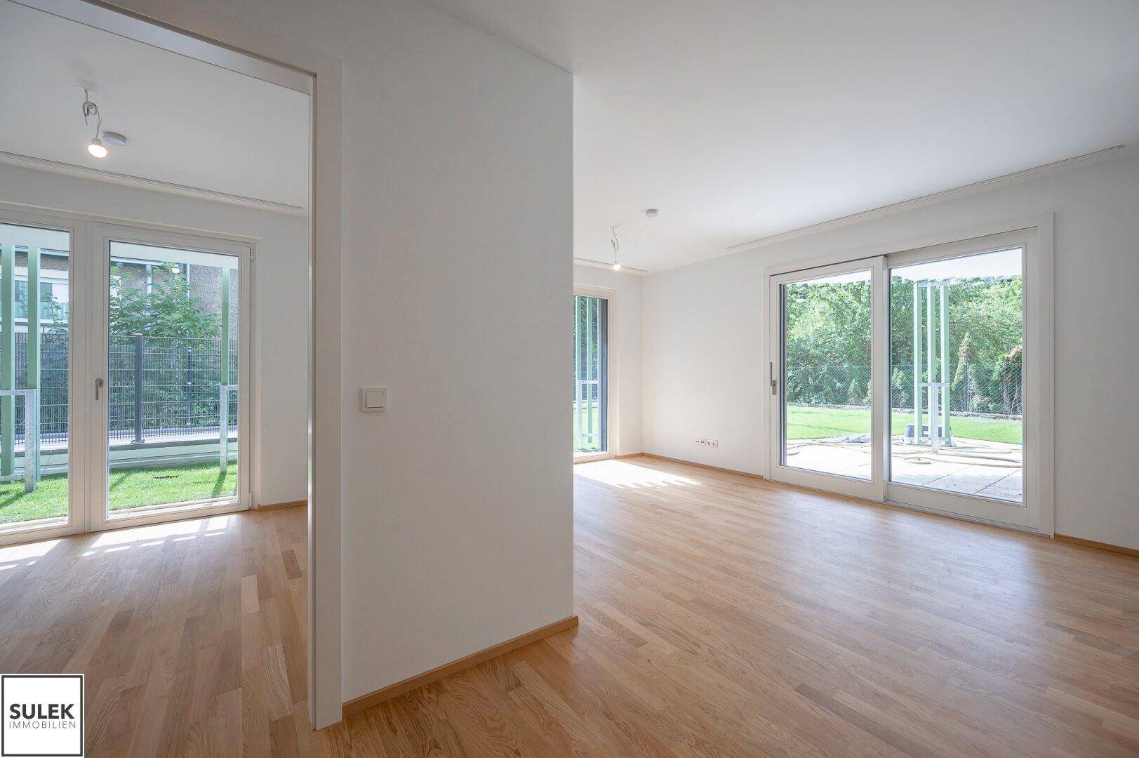 Geräumiger Wohnbereich mit Holzboden und mehreren Zugängen zu den Außenbereichen.