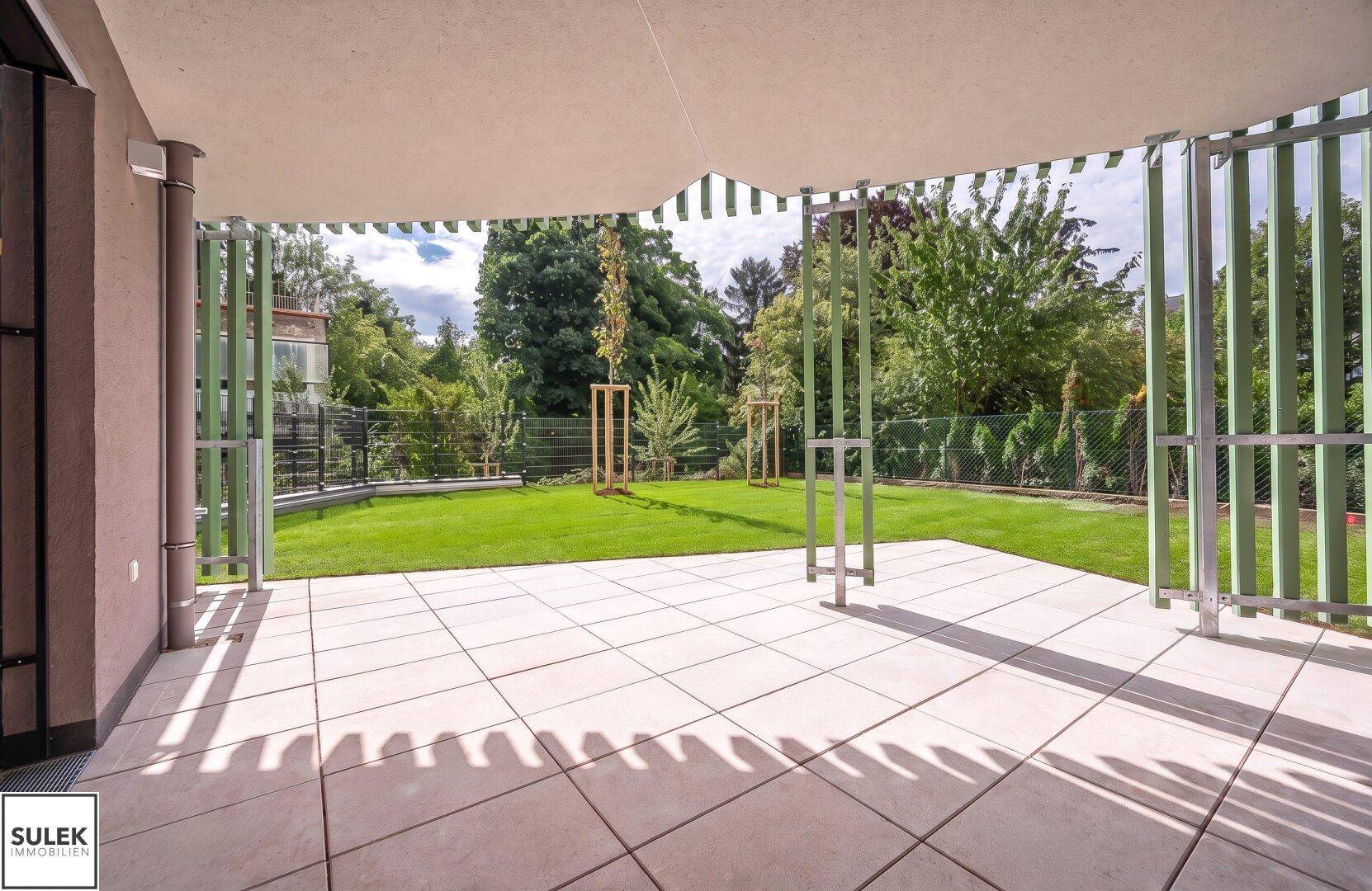 Geräumige, geflieste Terrasse mit Sonnenschutz und direktem Zugang zum privaten Gartenbereich.