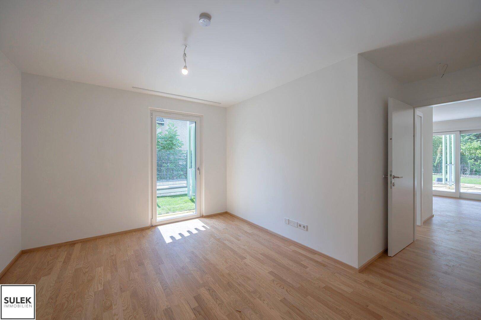 Helles Zimmer mit Holzboden und Fenster mit Blick ins Grüne, ideal als Schlaf- oder Arbeitszimmer.