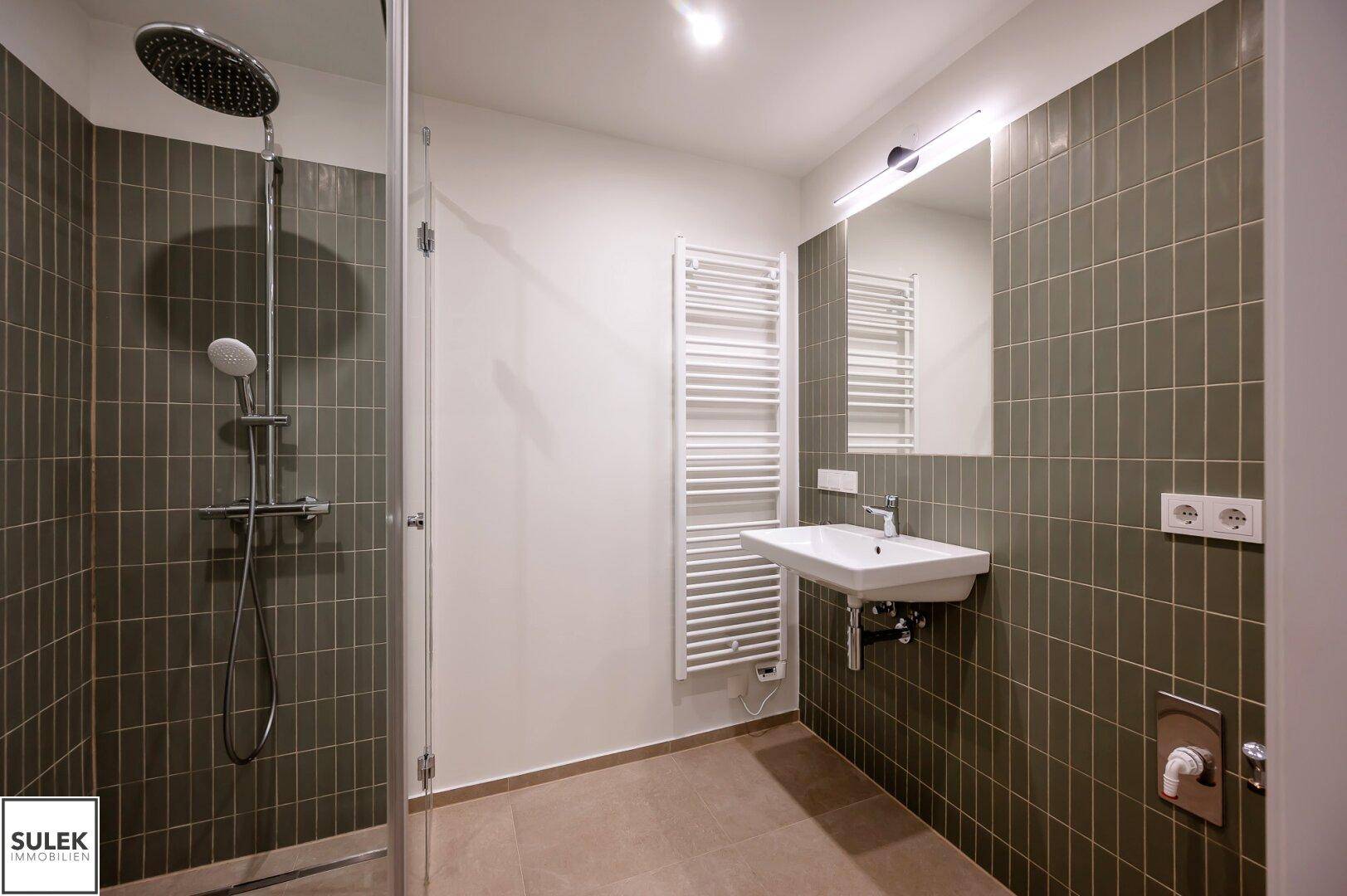 Modernes Badezimmer mit großer Regendusche, Einzelwaschbecken und beheiztem Handtuchhalter.