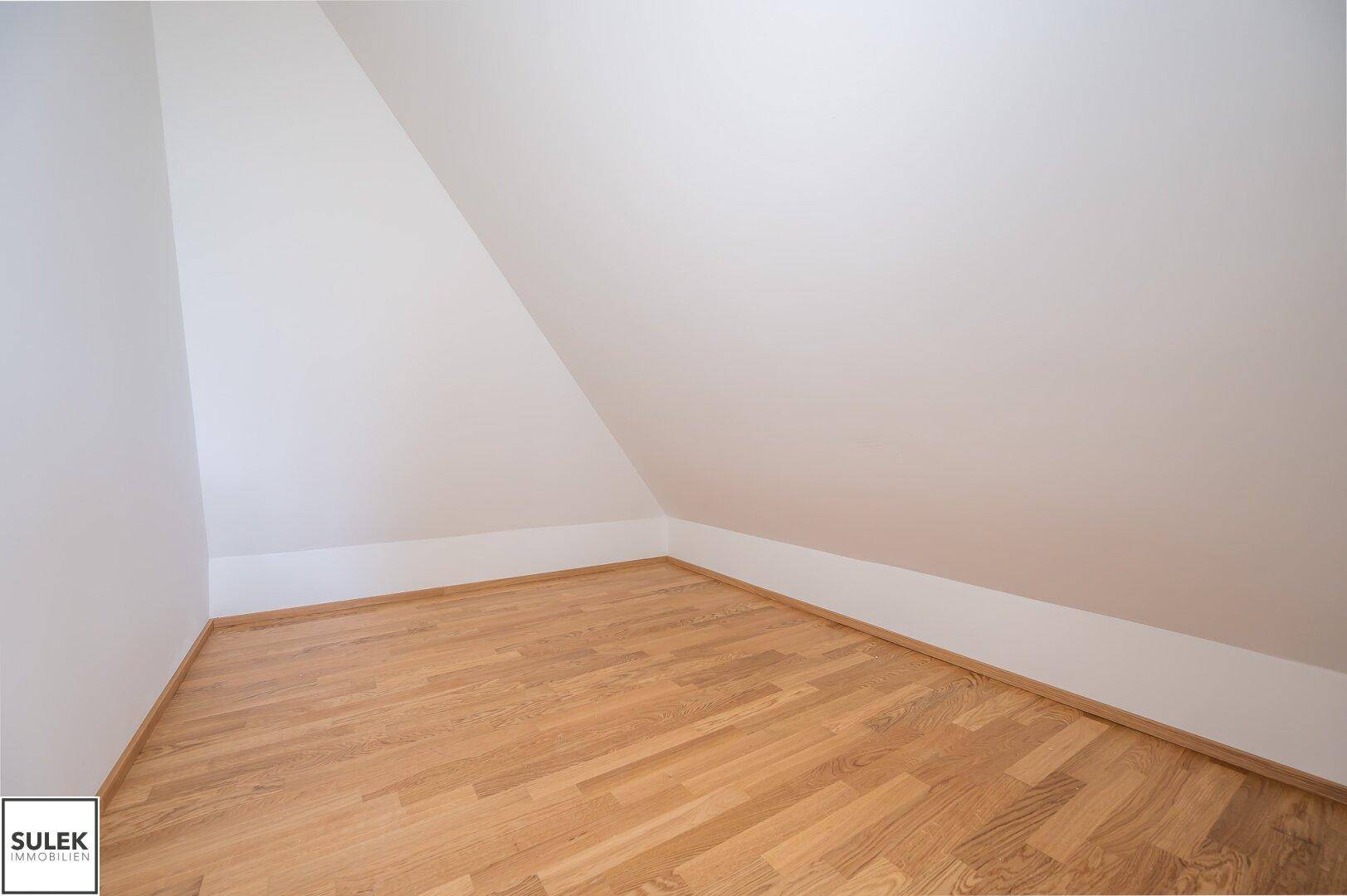 Kleiner, heller Raum im Dachgeschoss mit Holzboden und schrägen Wänden.