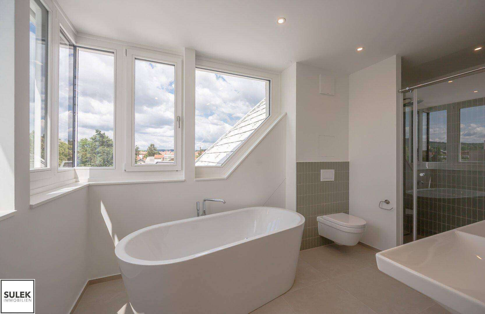 Helles Badezimmer mit freistehender Badewanne, wandhängendem WC und separater Dusche.