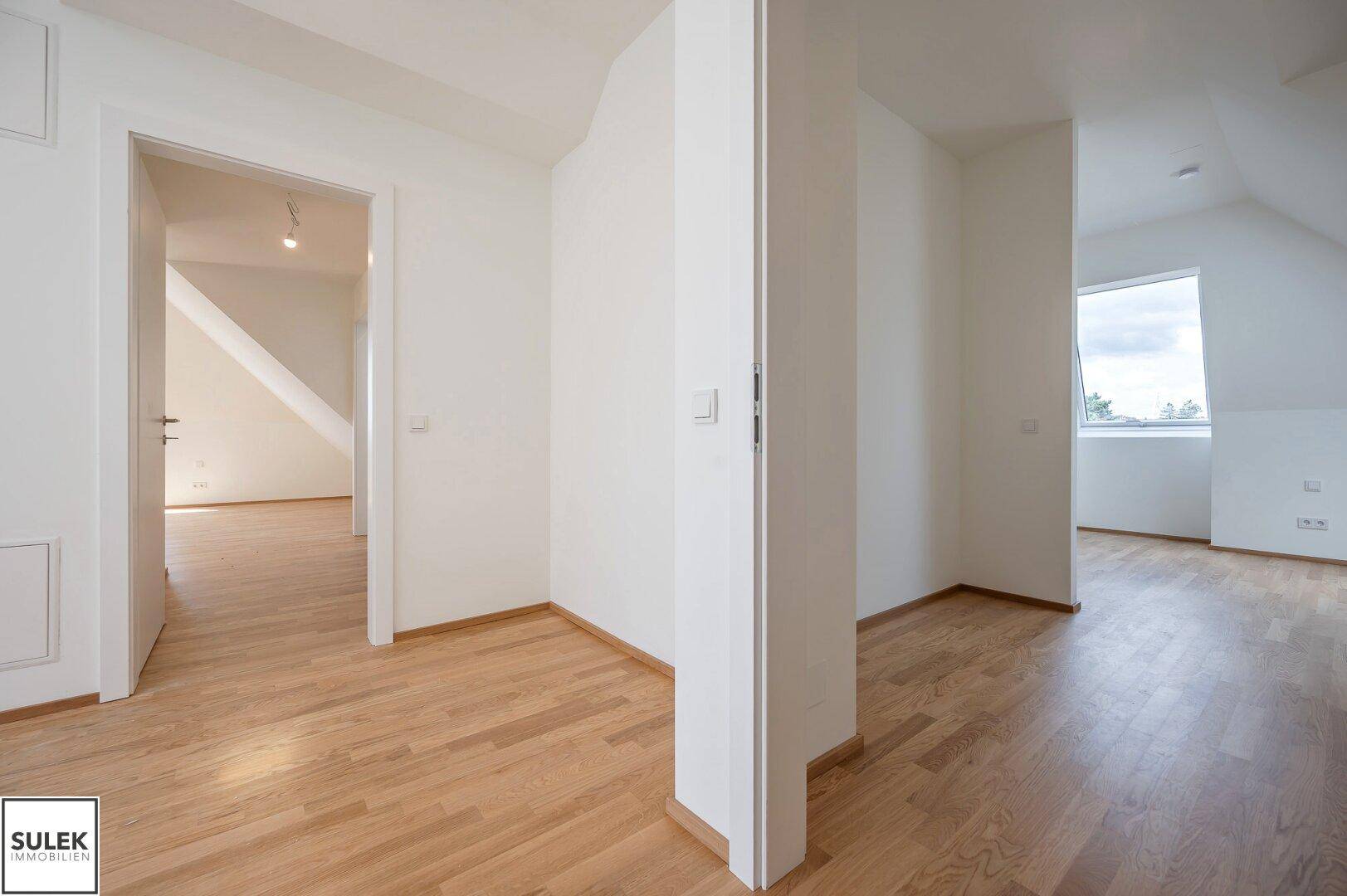 Heller Übergangsbereich mit Holzboden und Zugang zu weiteren Zimmern im Dachgeschoss.