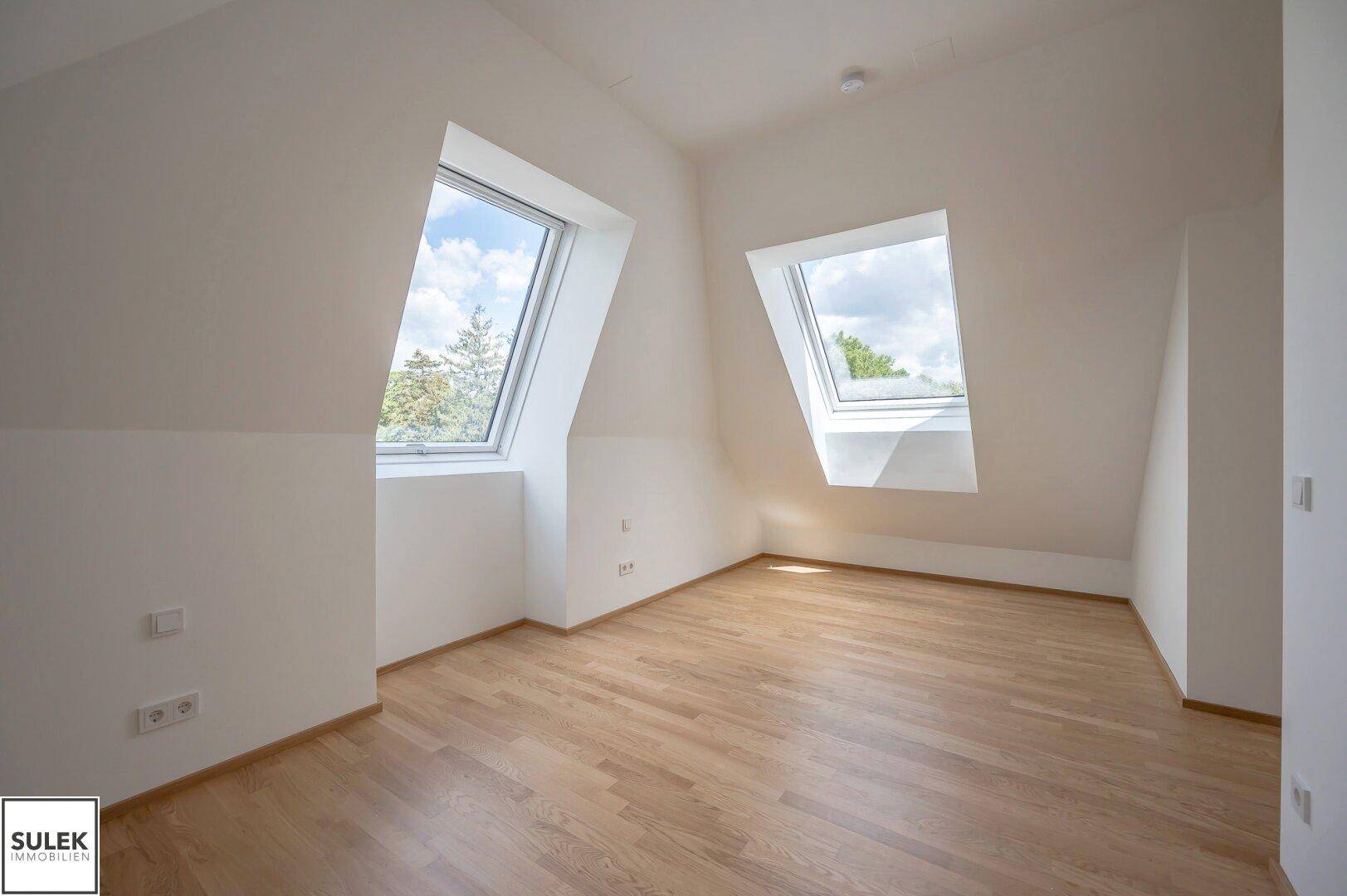 Geräumiges Schlafzimmer im Dachgeschoss mit Holzboden und zwei großen Dachfenstern.
