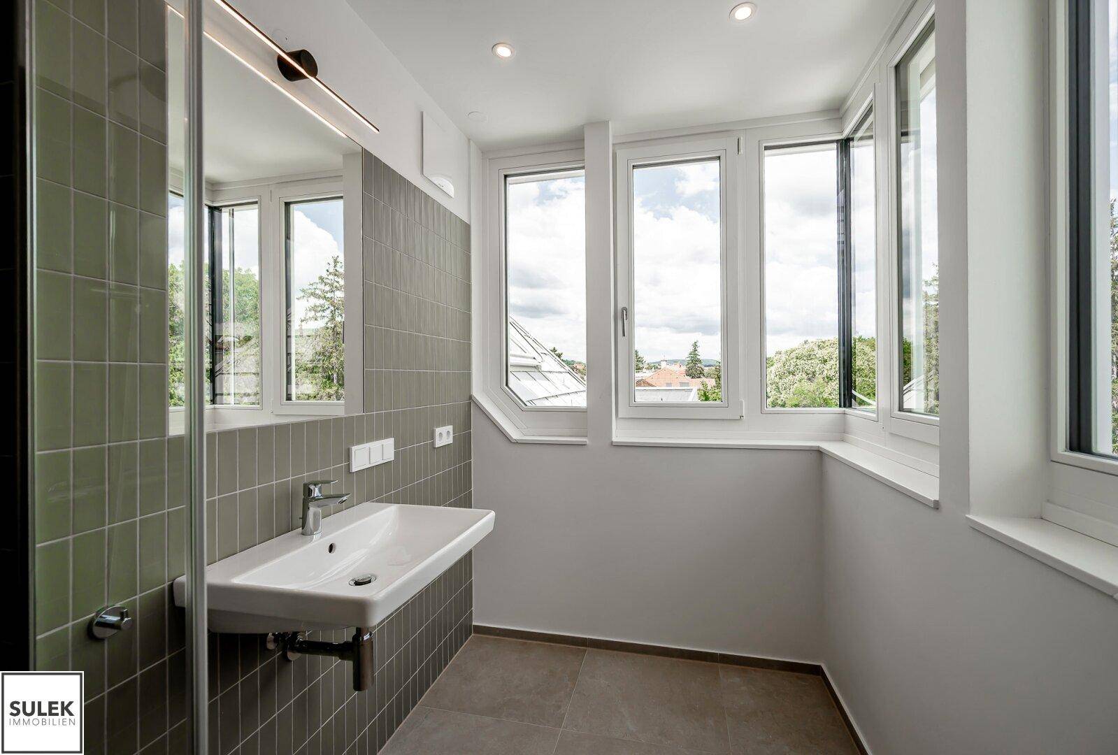 Modernes Badezimmer mit Einzelwaschbecken, großem Spiegel und großen Fenstern.
