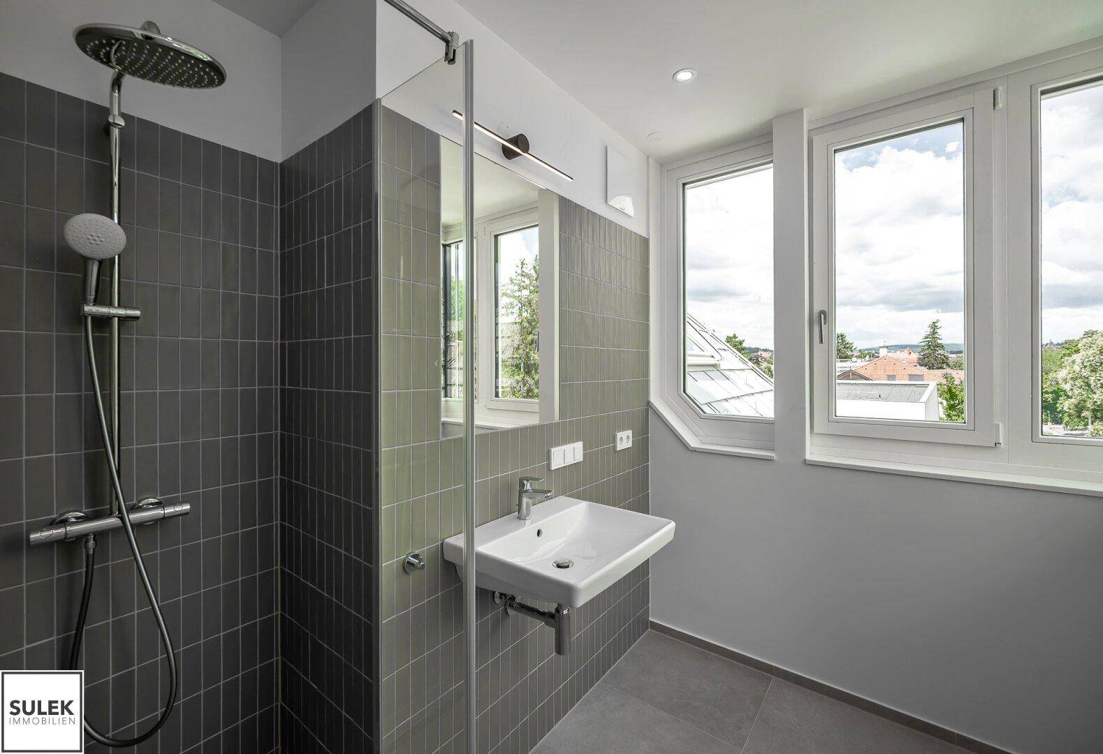 Moderne Dusche mit Regenduschkopf, Einzelwaschbecken und großen Fenstern.